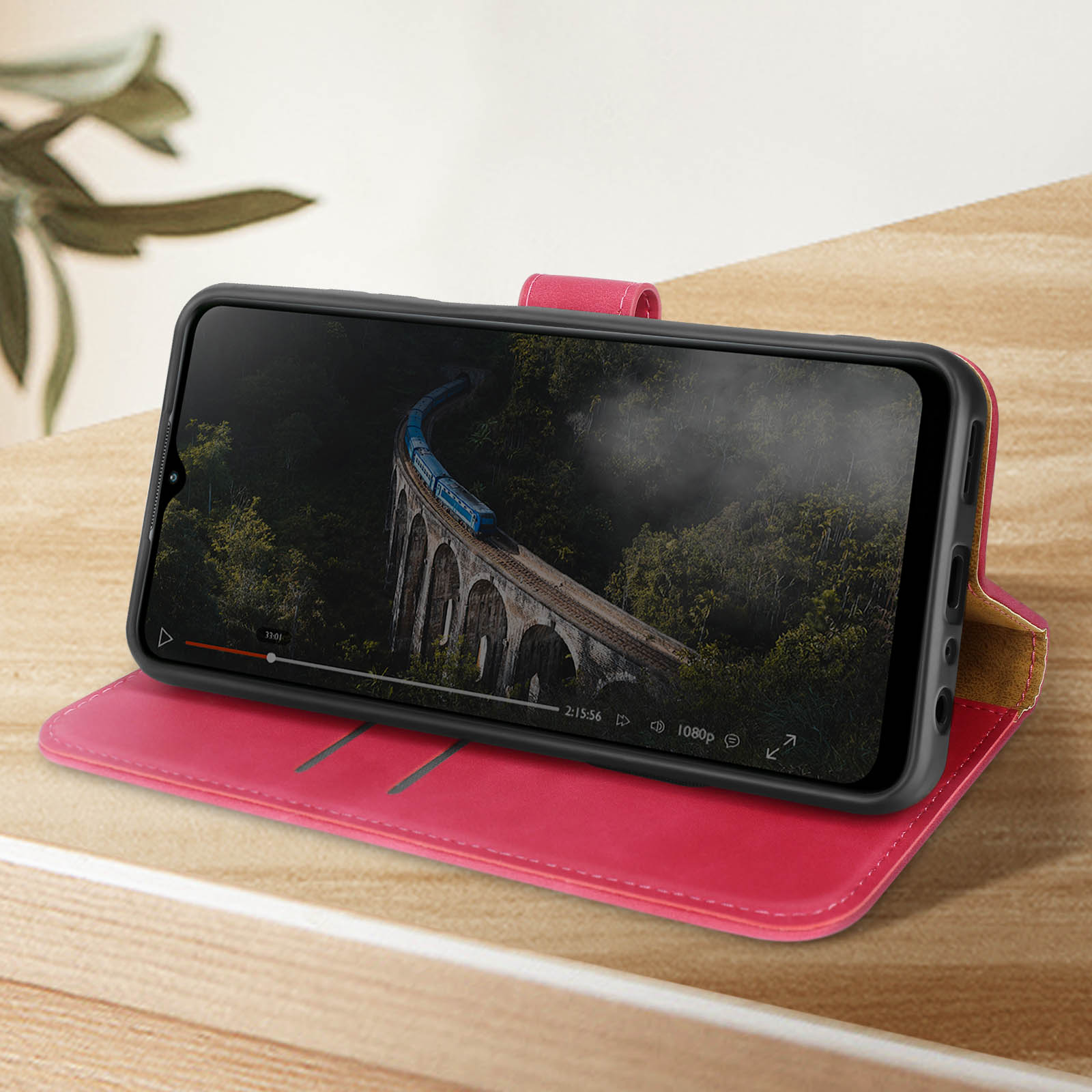 Telefono in una custodia rossa che mostra un treno su un ponte sopra una foresta.
