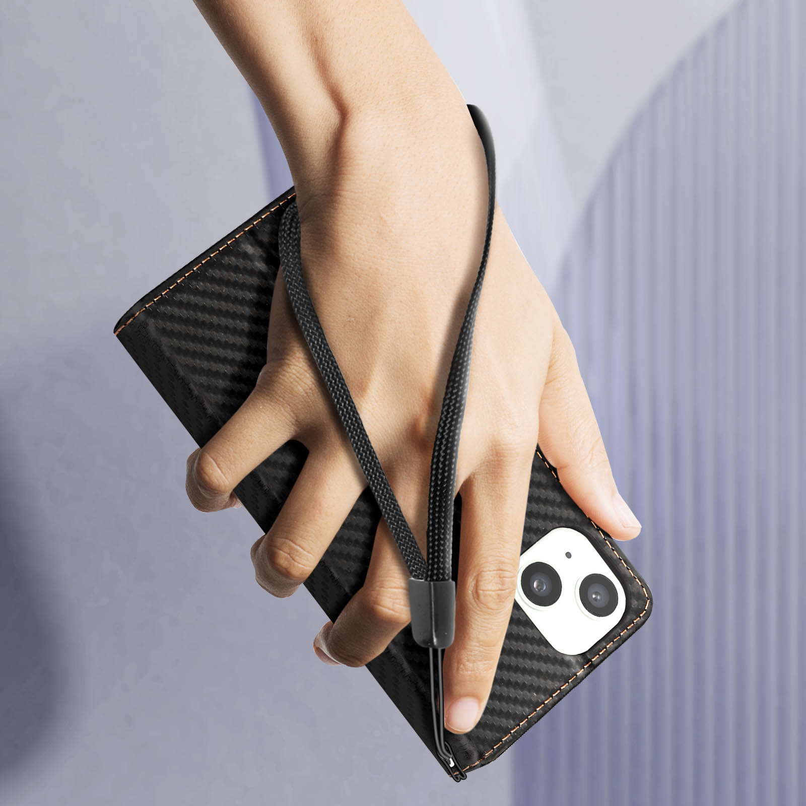 Eine Hand, die eine schwarze Handyhülle mit Handschlaufe hält.