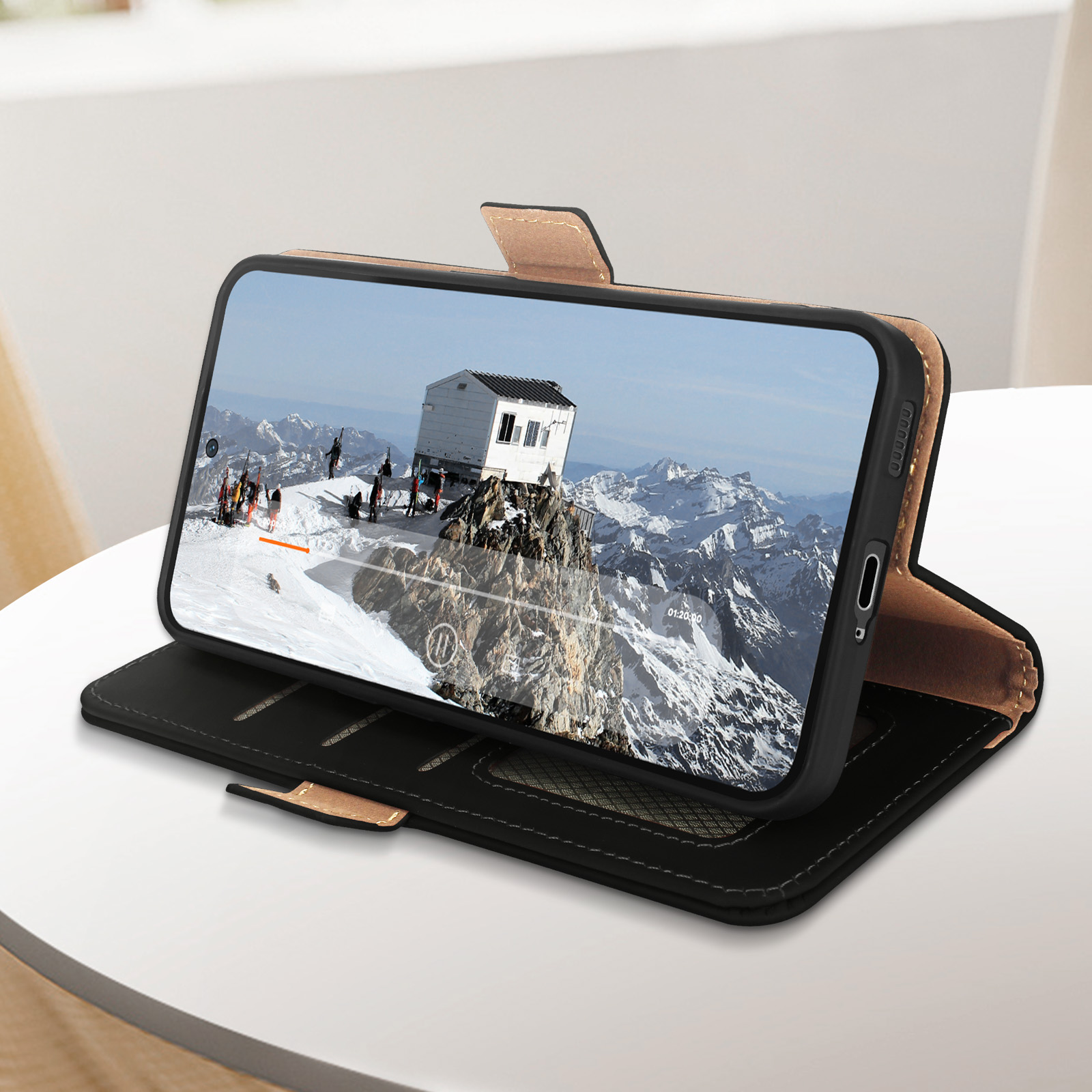 Telefono in una custodia a portafoglio marrone e nera che mostra una scena di montagna innevata.