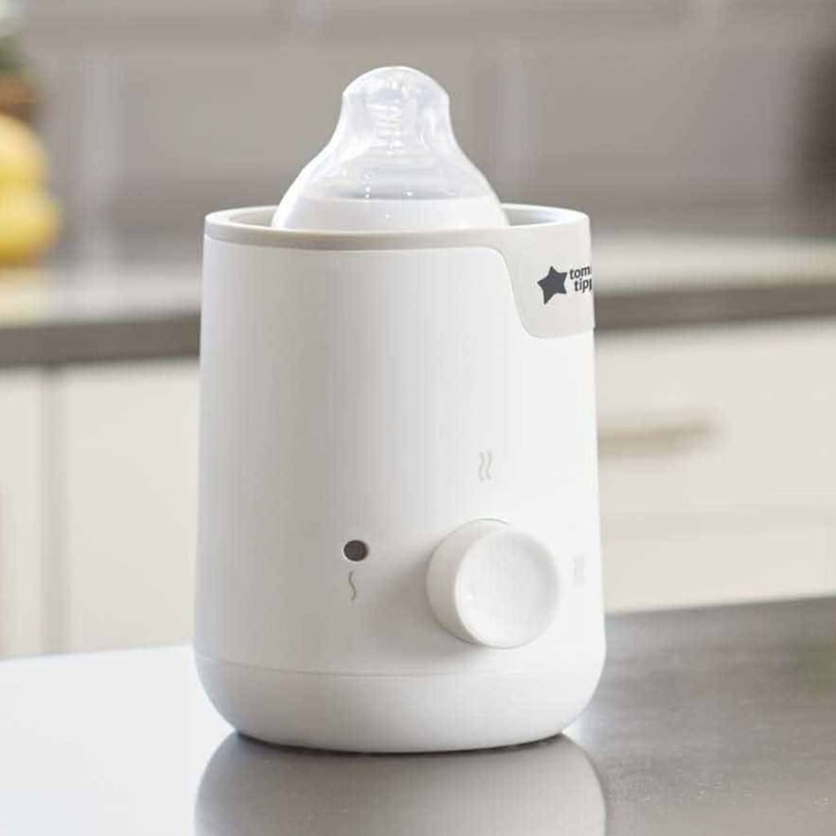 Weißer Babyflaschenwärmer mit Flasche. Ein Drehregler ist sichtbar. Küchenhintergrund.