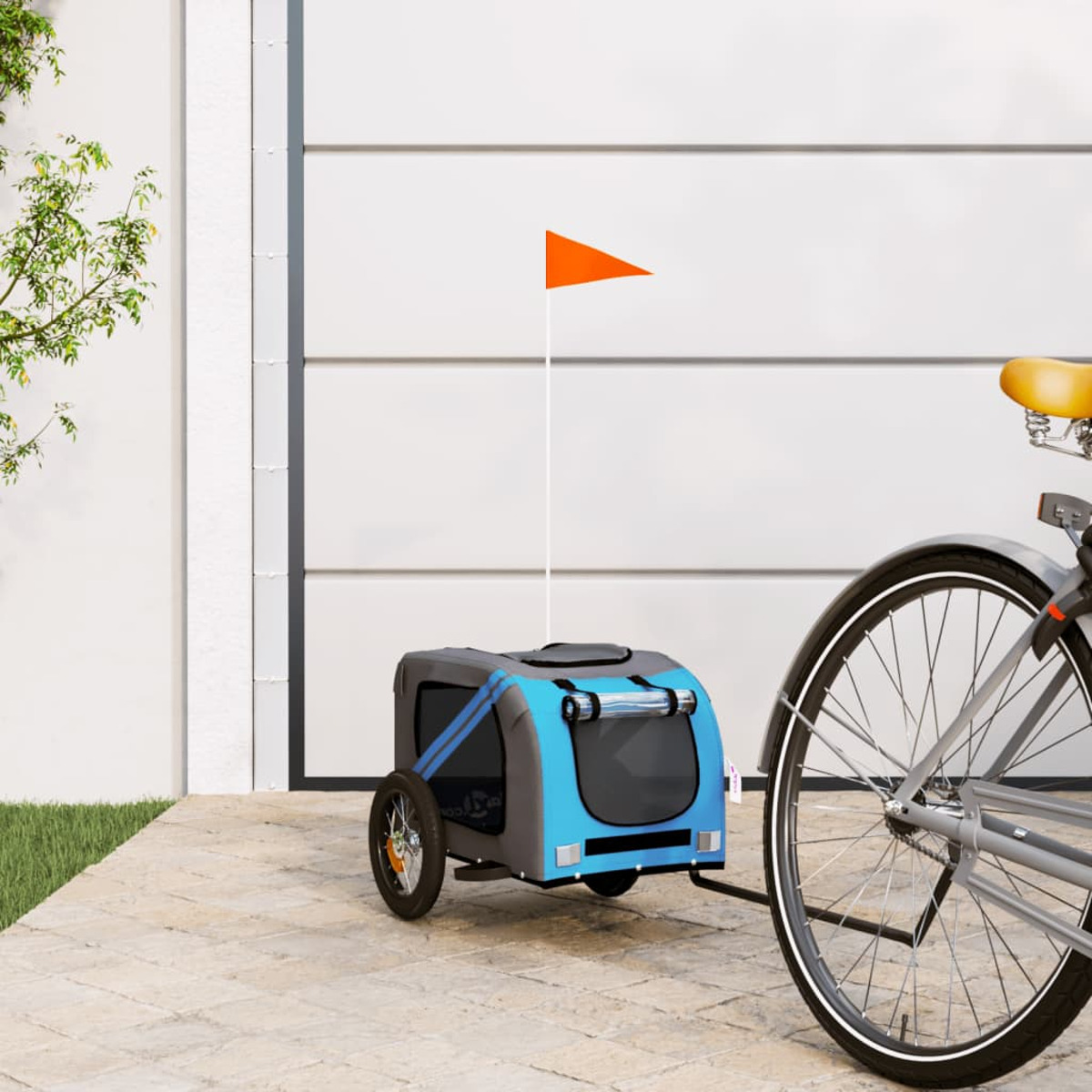 Ein blau-grauer Haustieranhänger, der mit einer orangefarbenen Flagge an einem Fahrrad befestigt ist.