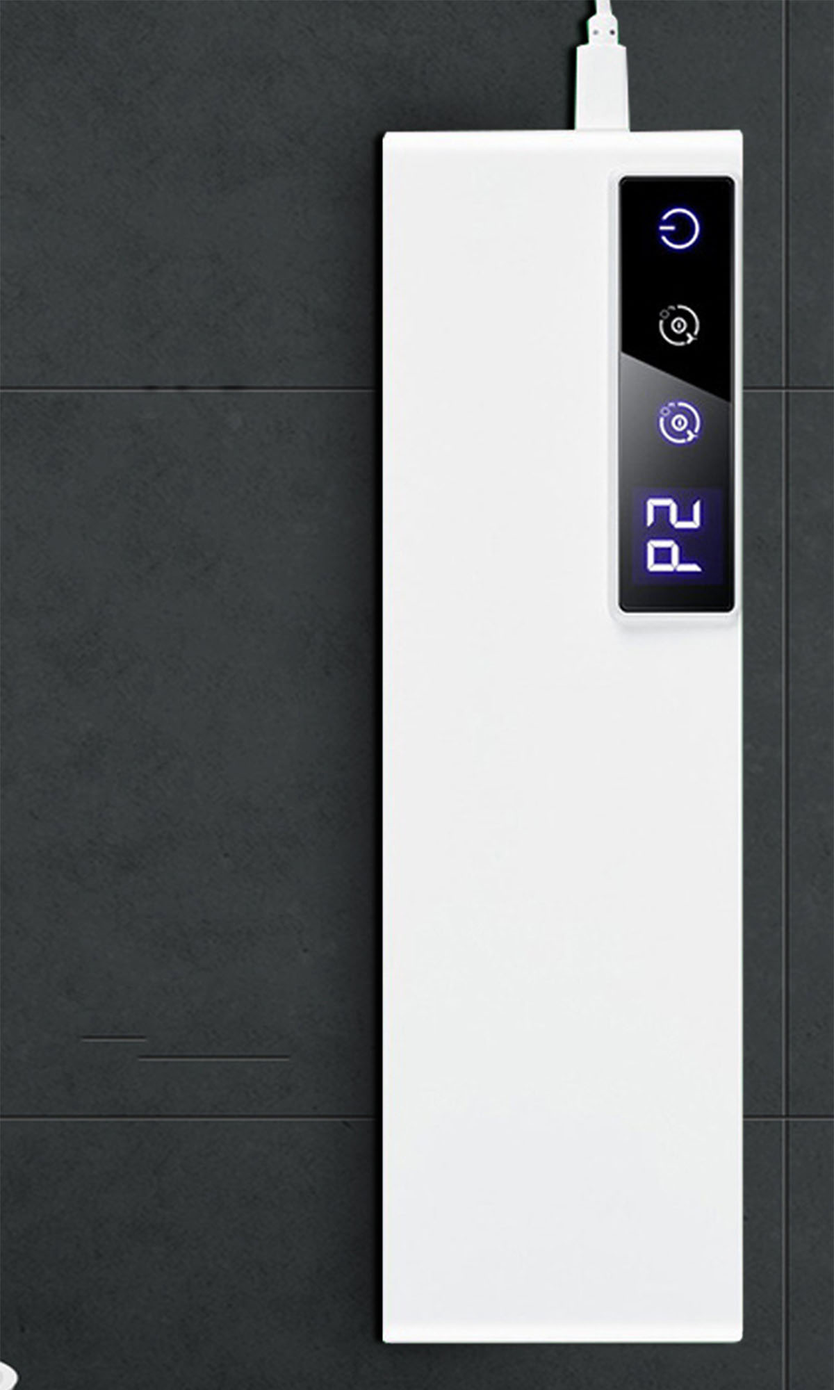 Weißes rechteckiges Gerät an einer dunklen Fliesenwand mit digitaler Anzeige und USB-Kabel.