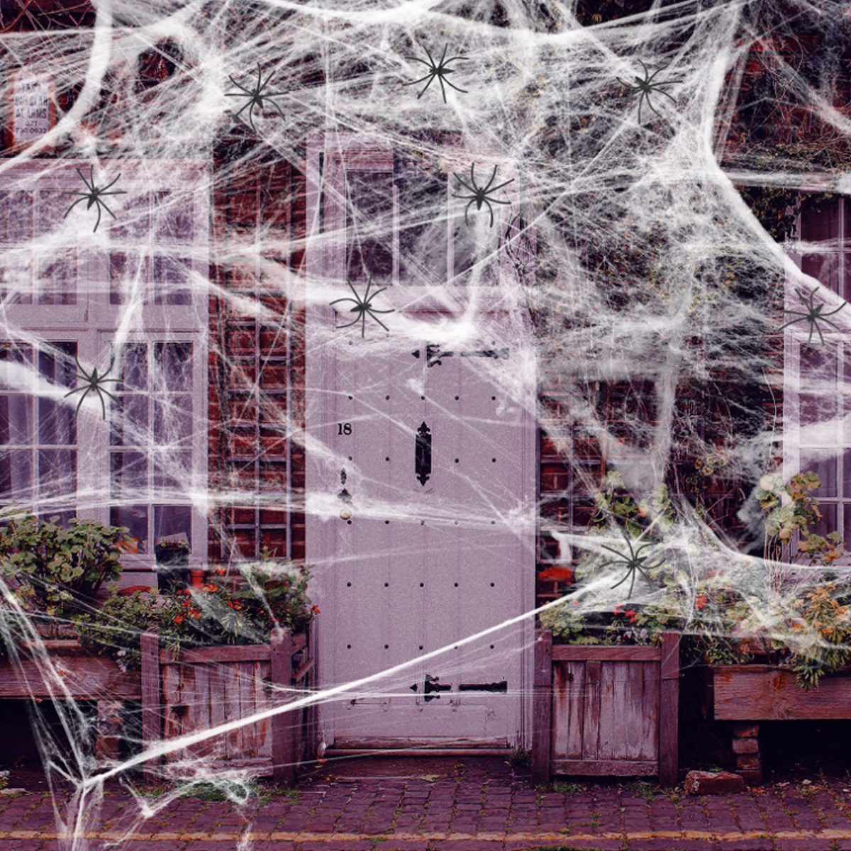 Ein Gebäude mit Spinnweben und Spinnen als Halloween-Dekorationen. Die Tür hat die Nummer 18.