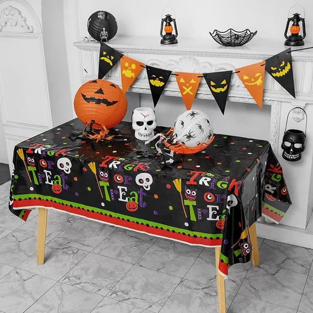 Halloween-Tischdeko mit Kürbissen, Totenköpfen und Girlanden. Dekorationen auf schwarzer Tischdecke.