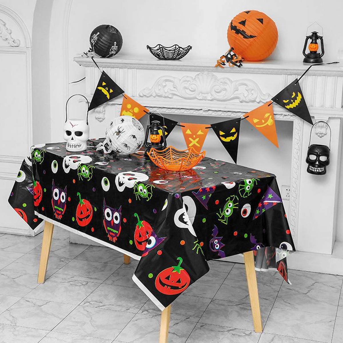 Eine Halloween-Tischdekoration mit Halloween-Dekorationen, Kürbissen, Totenköpfen und einer schwarzen Tischdecke.