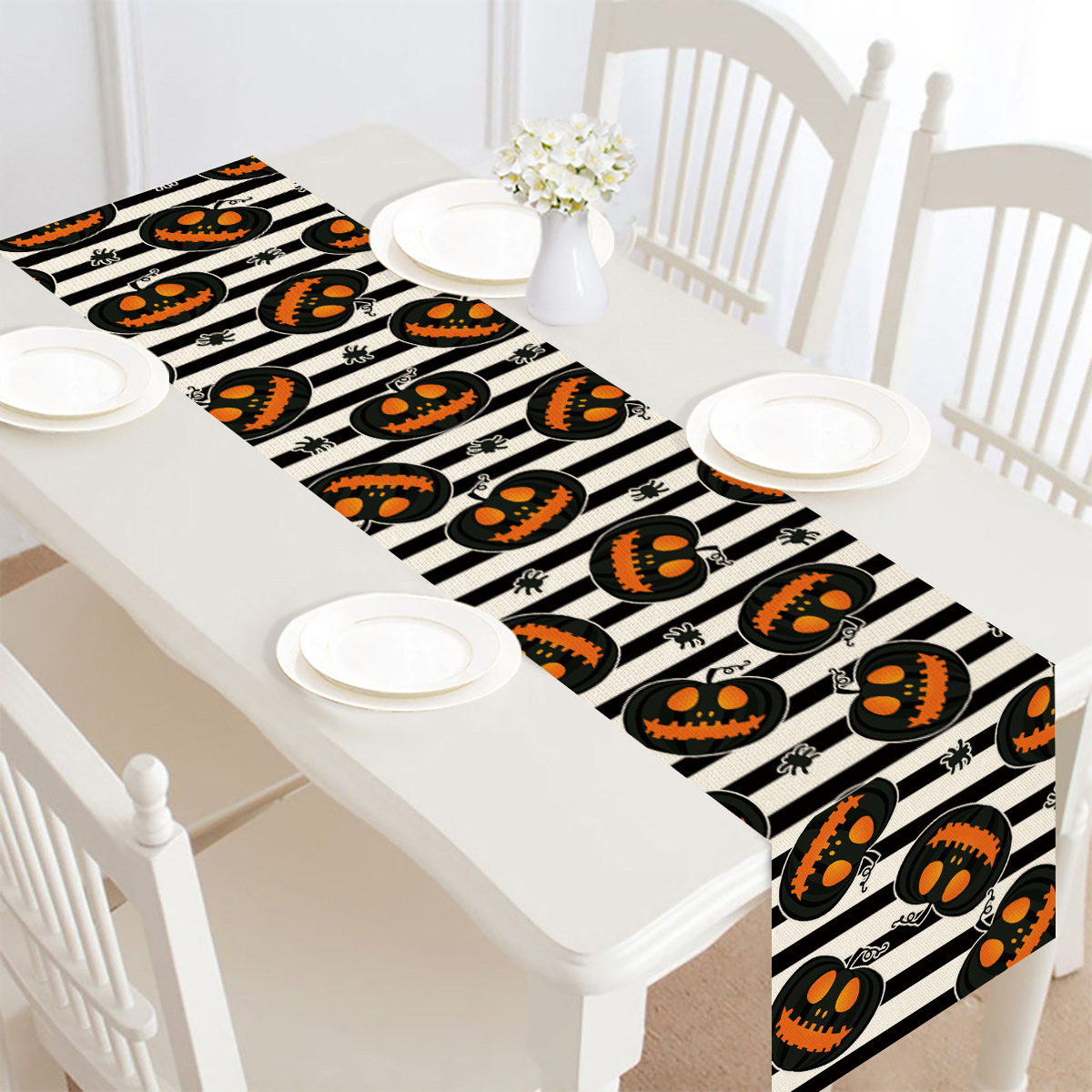 Halloween-Tischläufer mit Kürbissen und schwarzen Streifen auf einem weißen Tisch.