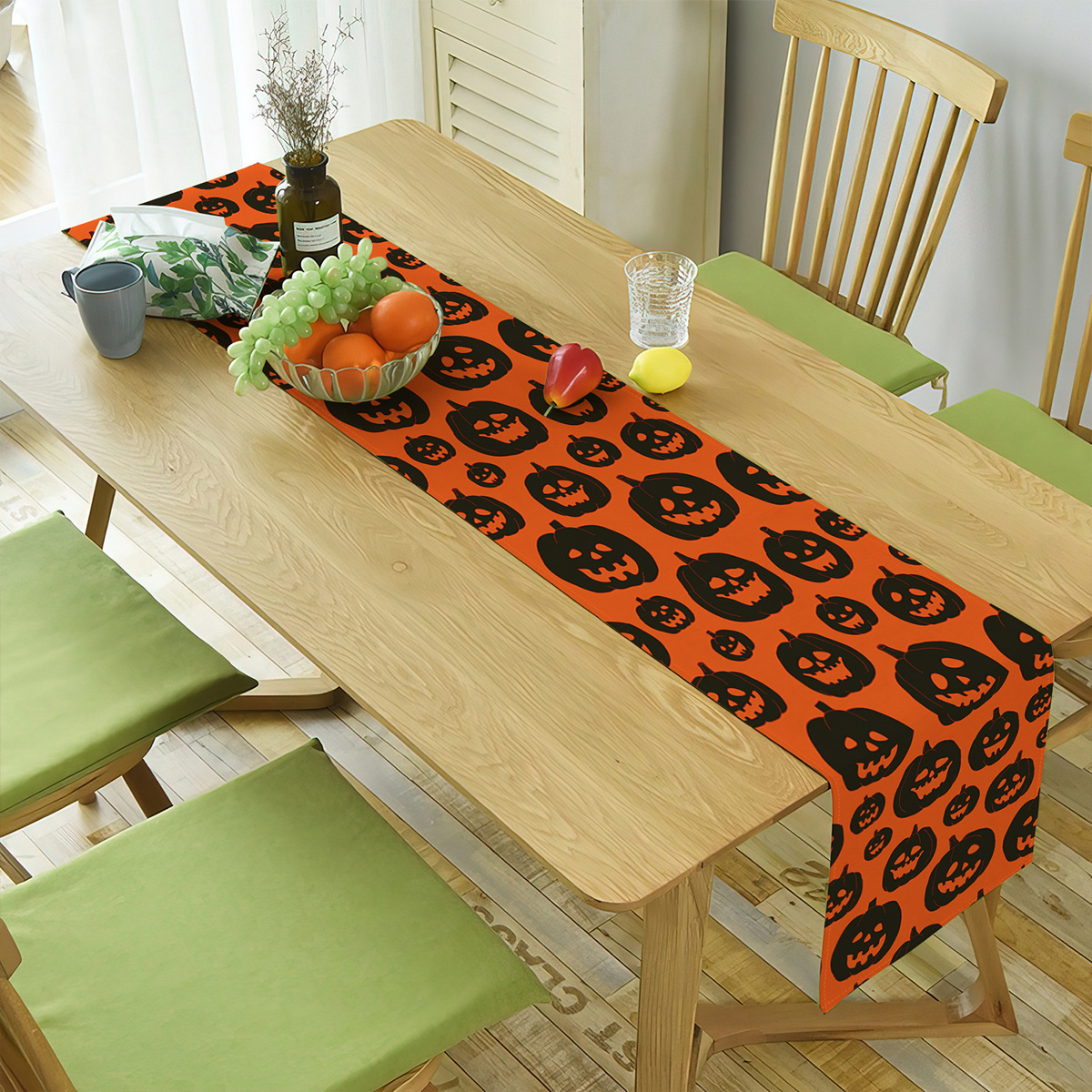 Oranger Halloween-Tischläufer mit Kürbis-Designs auf einem Holztisch.