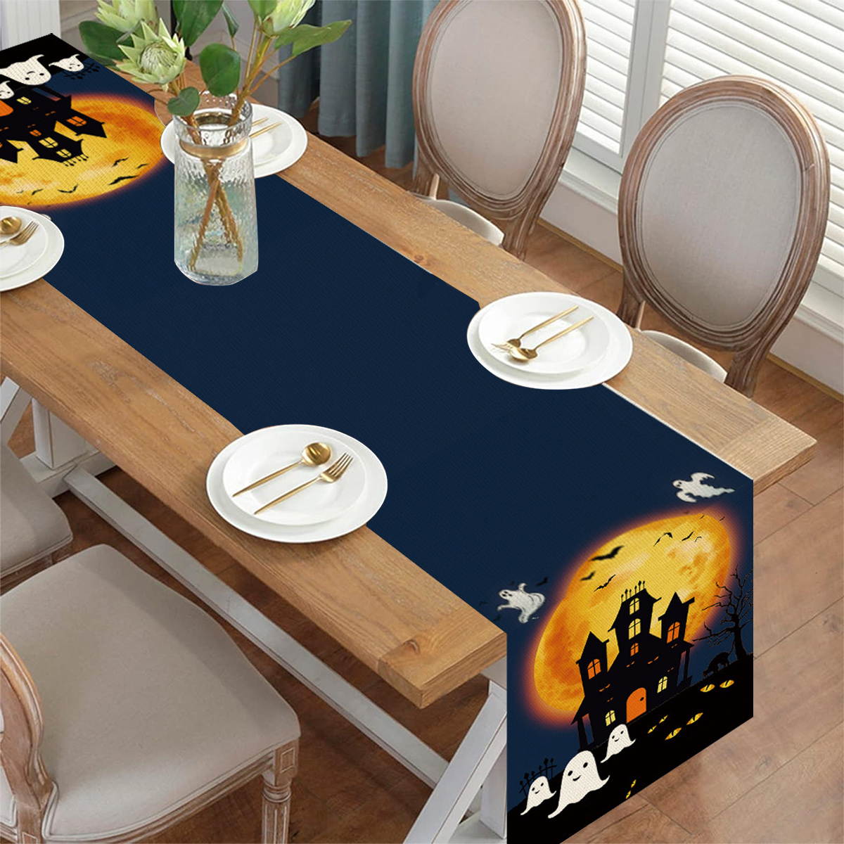 Ein Halloween-Tischläufer auf einem Holztisch mit Vollmond- und Geisterhaus-Design.