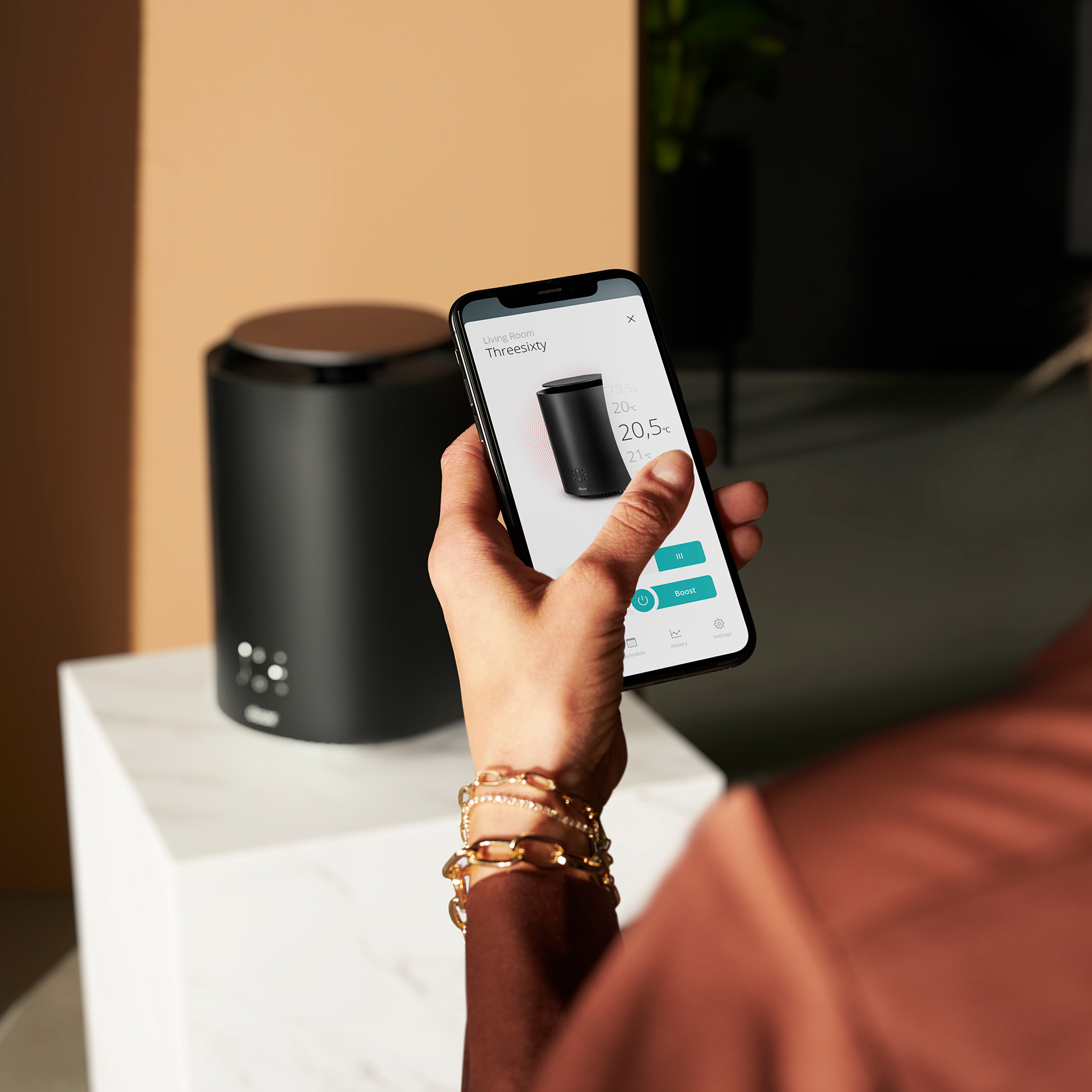 Personne tenant un téléphone près d'un haut-parleur noir.