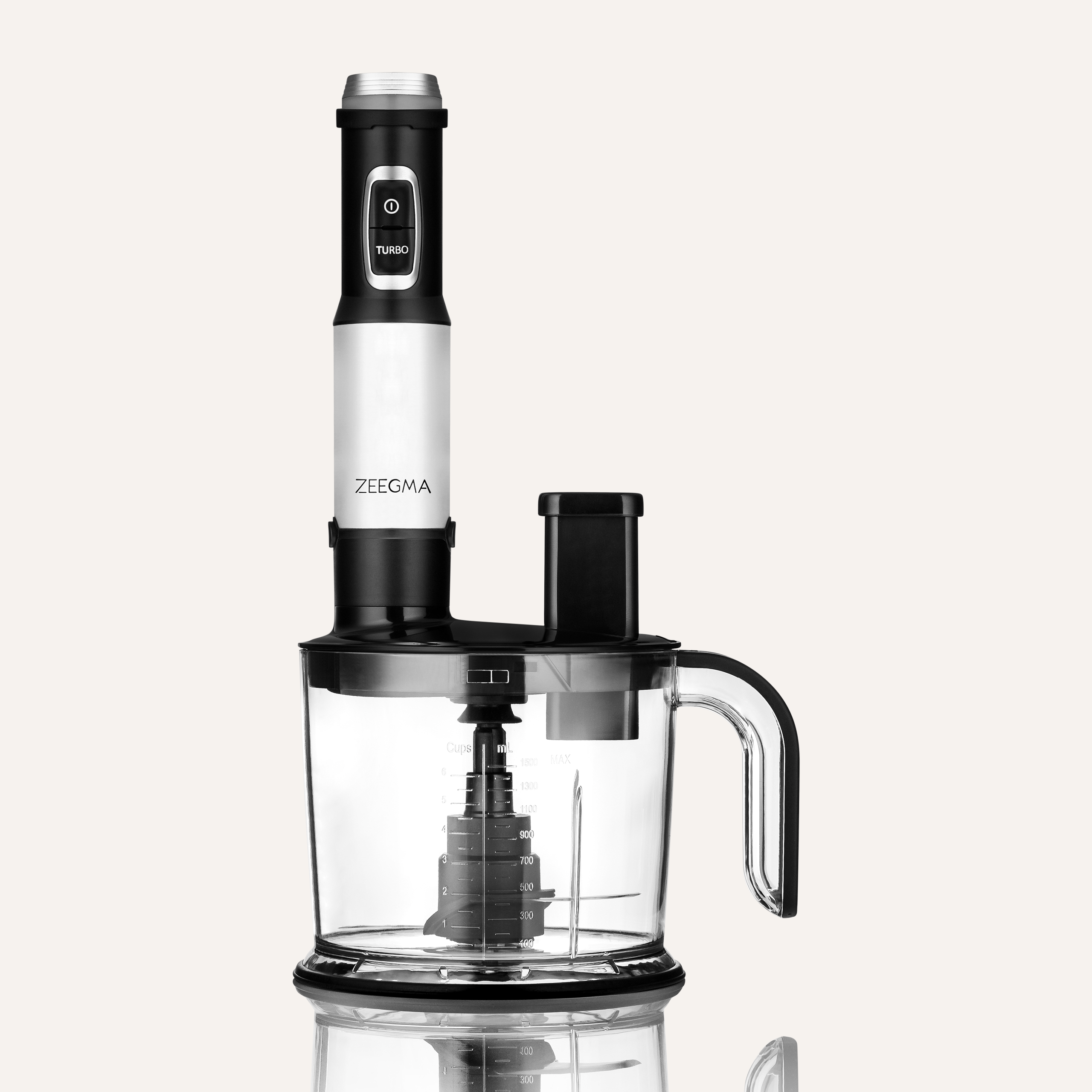 Czarny i biały robot kuchenny Zeegma z przezroczystym pojemnikiem. Tło jest białe.