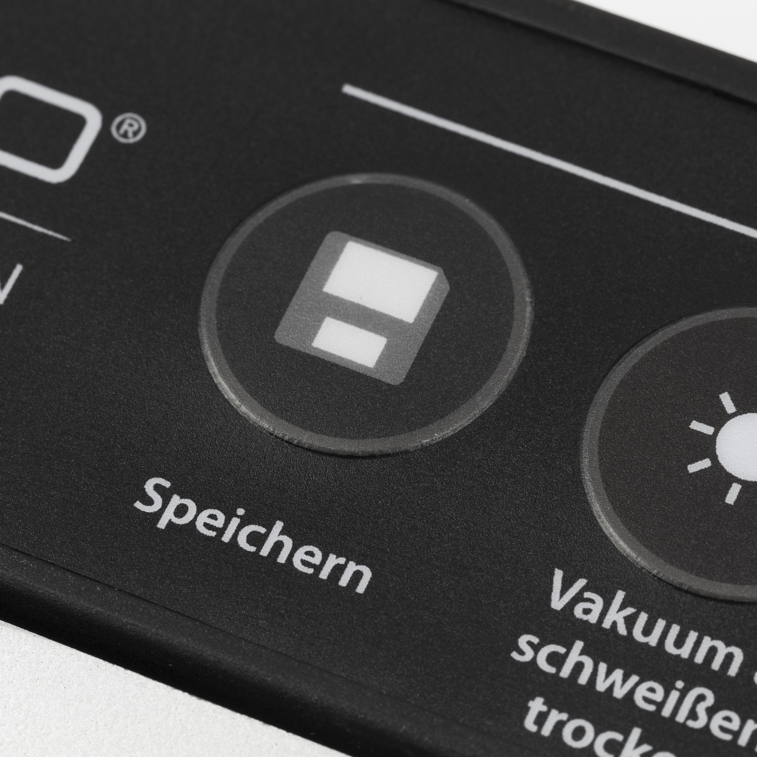 Nahaufnahme eines schwarzen Bedienfelds. Weißer Text 'Speichern' und ein Lichtsymbol sichtbar.