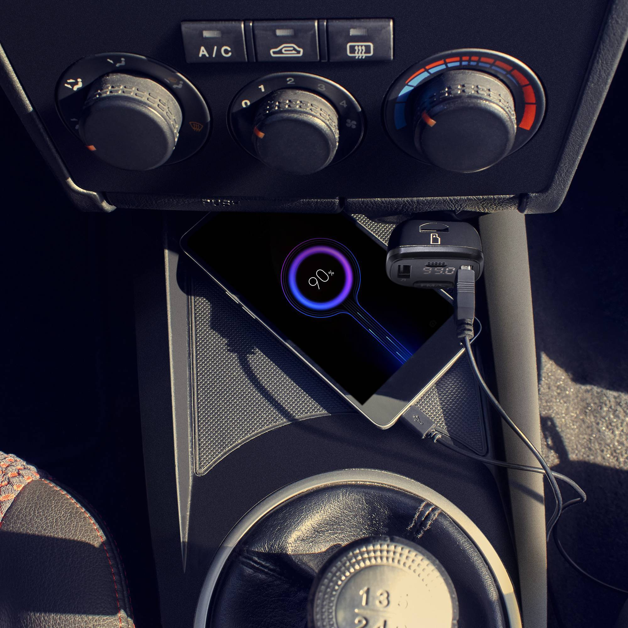 Un teléfono cargando en un coche. El teléfono muestra un porcentaje de carga del 90%.