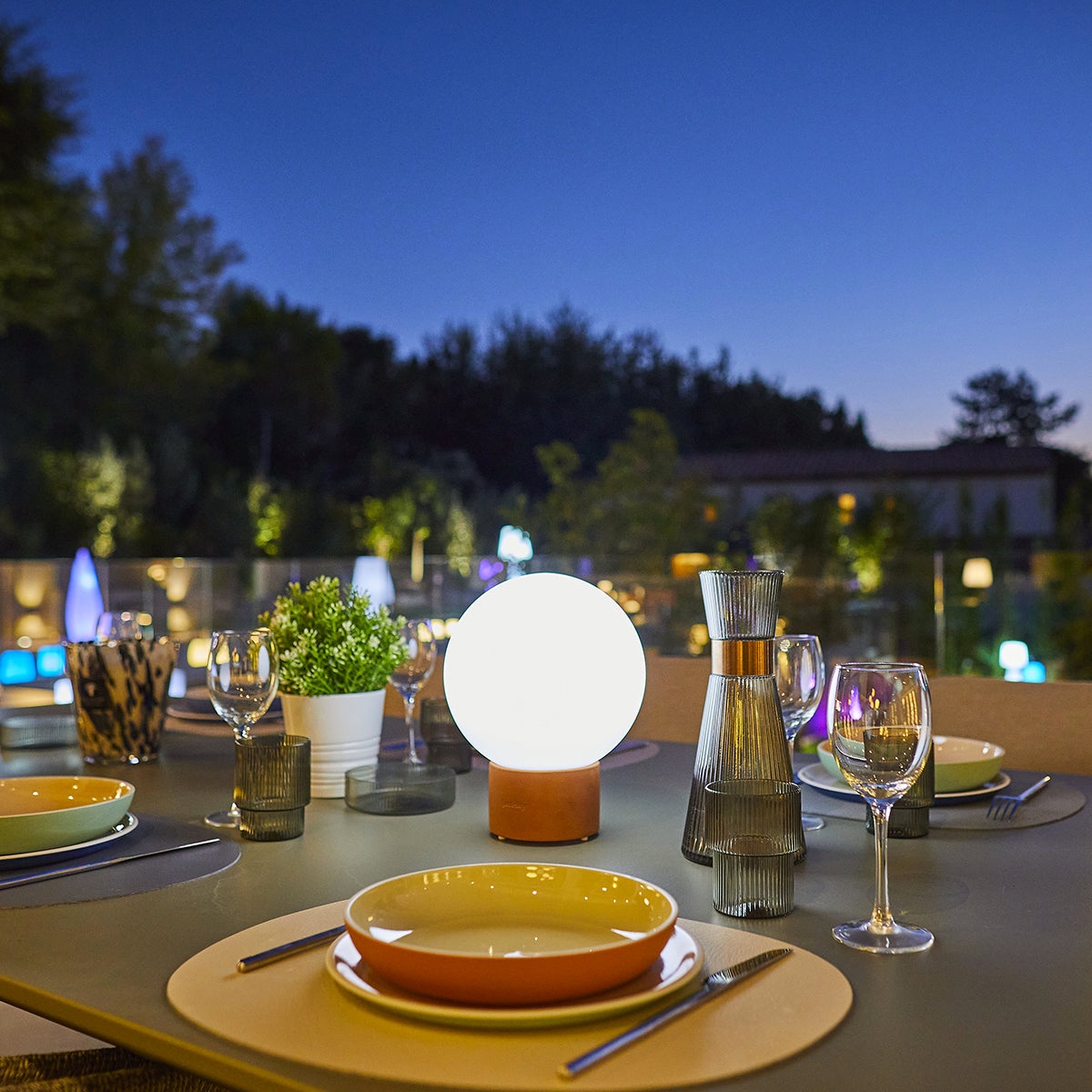 Ein Tisch für ein Abendessen mit einer hellen Kugellampe als zentrale Lichtquelle.