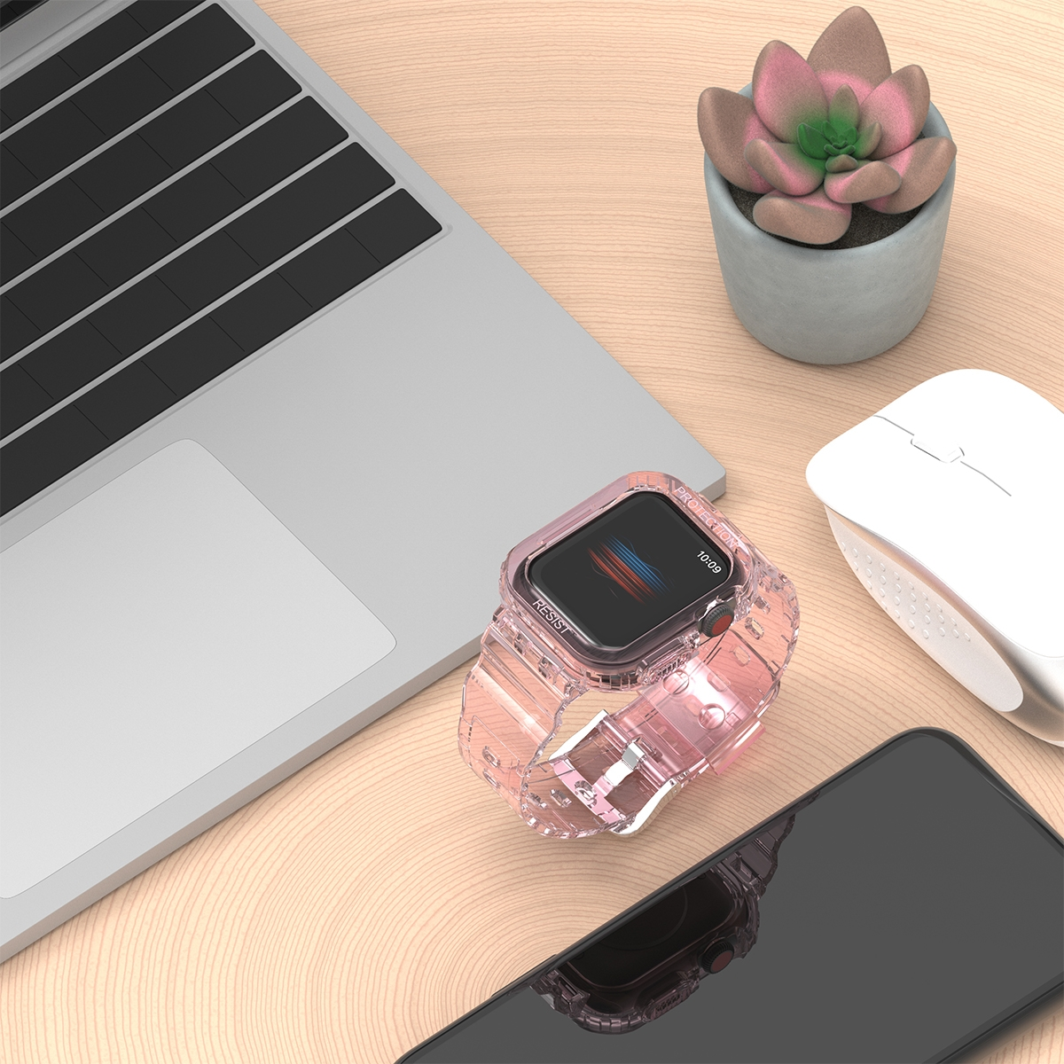 Rosa Uhr auf einem Holztisch mit Laptop, Maus und Telefon. Eine kleine Pflanze steht auch auf dem Tisch.