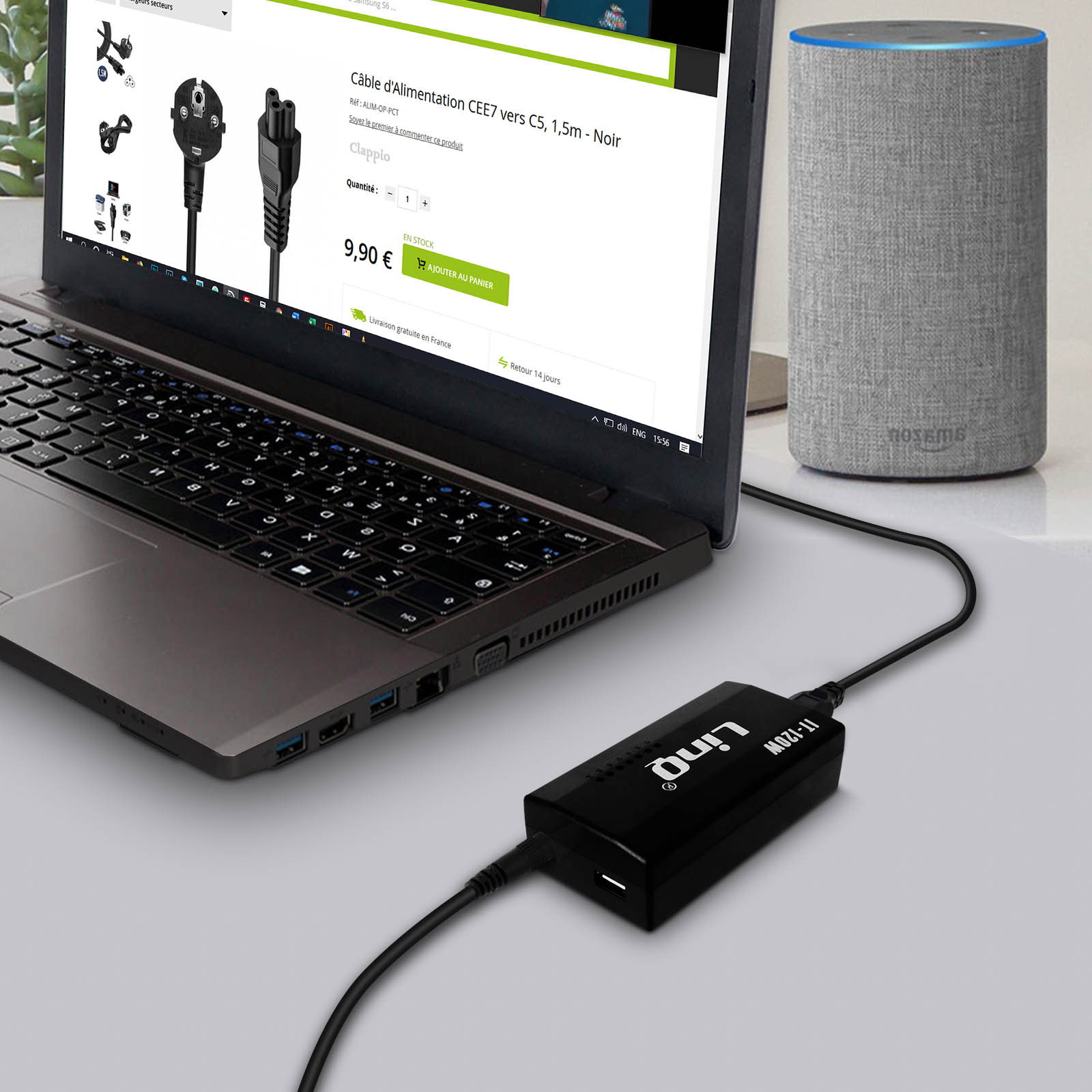 Ordenador portátil conectado a un altavoz con un adaptador de corriente y un cable.