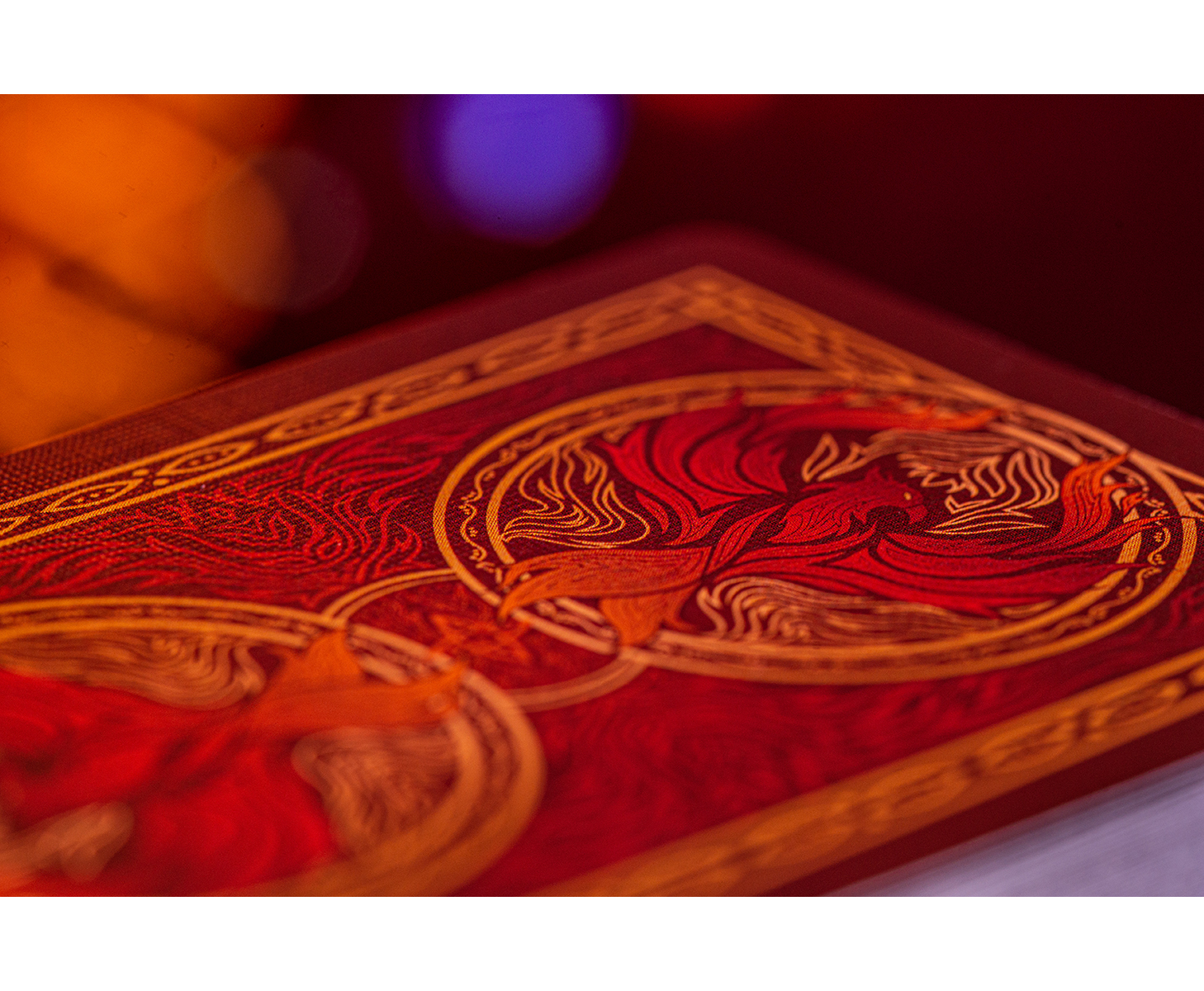 Nahaufnahme eines rot-goldenen Buches mit Phönix-Design und verschwommenem Hintergrund.