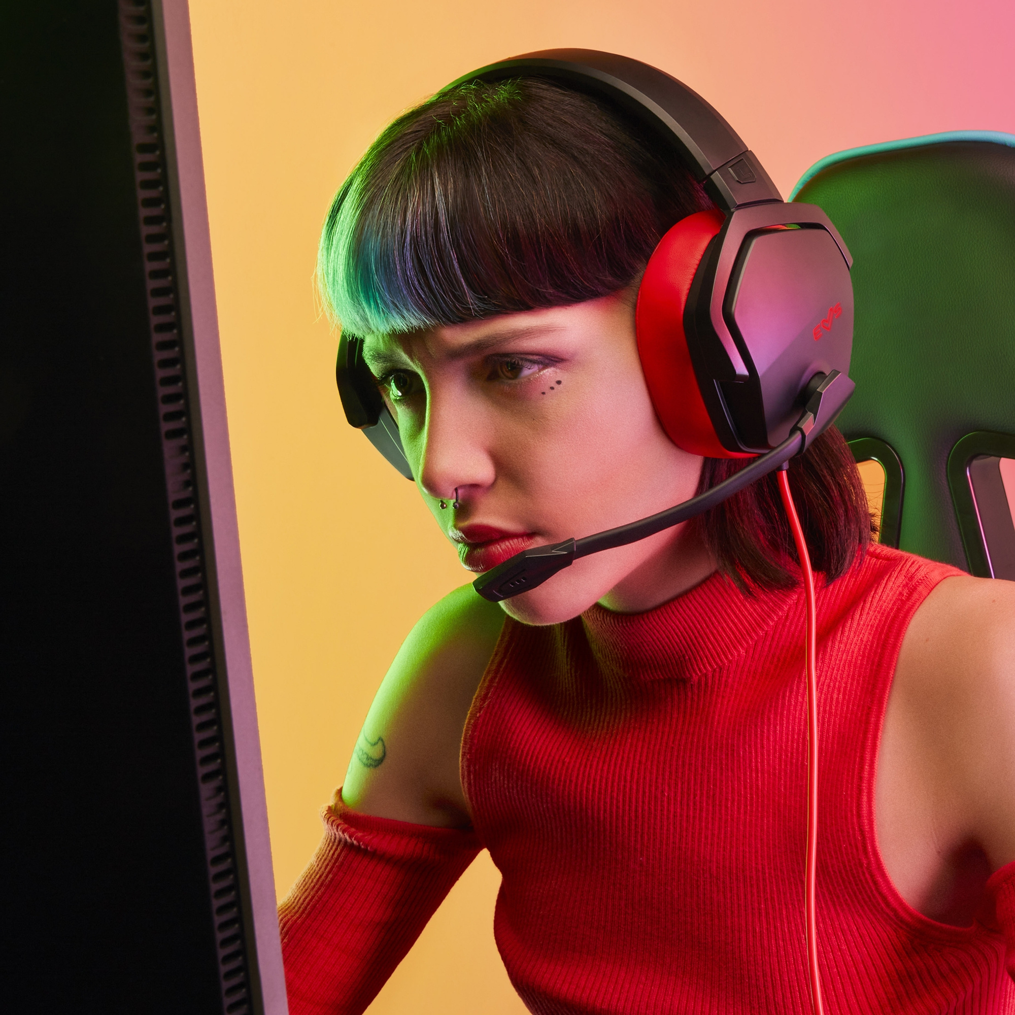 Una persona con auriculares, mirando intensamente una pantalla, con un fondo colorido.