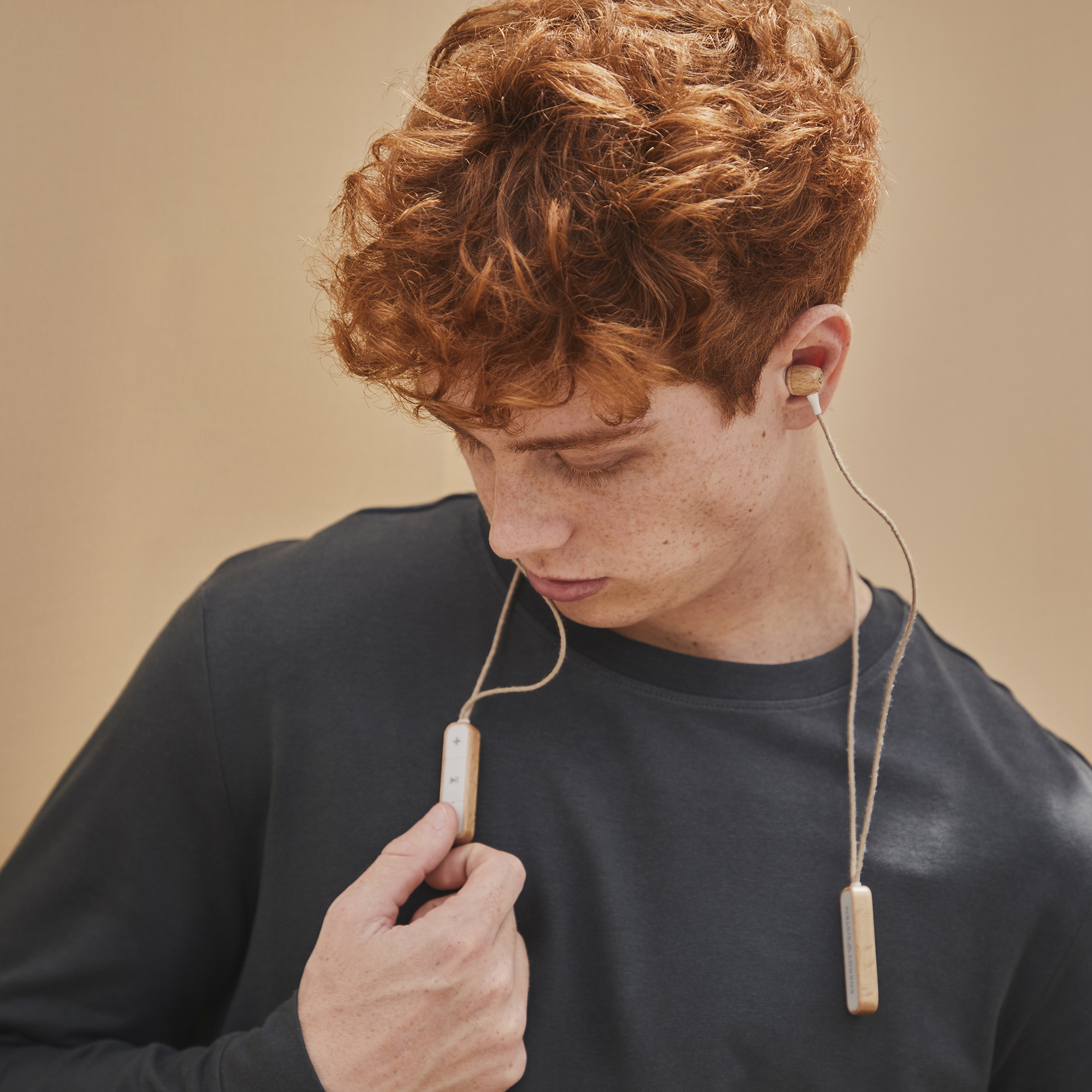 Hombre pelirrojo, camisa gris oscuro, usando auriculares de madera.