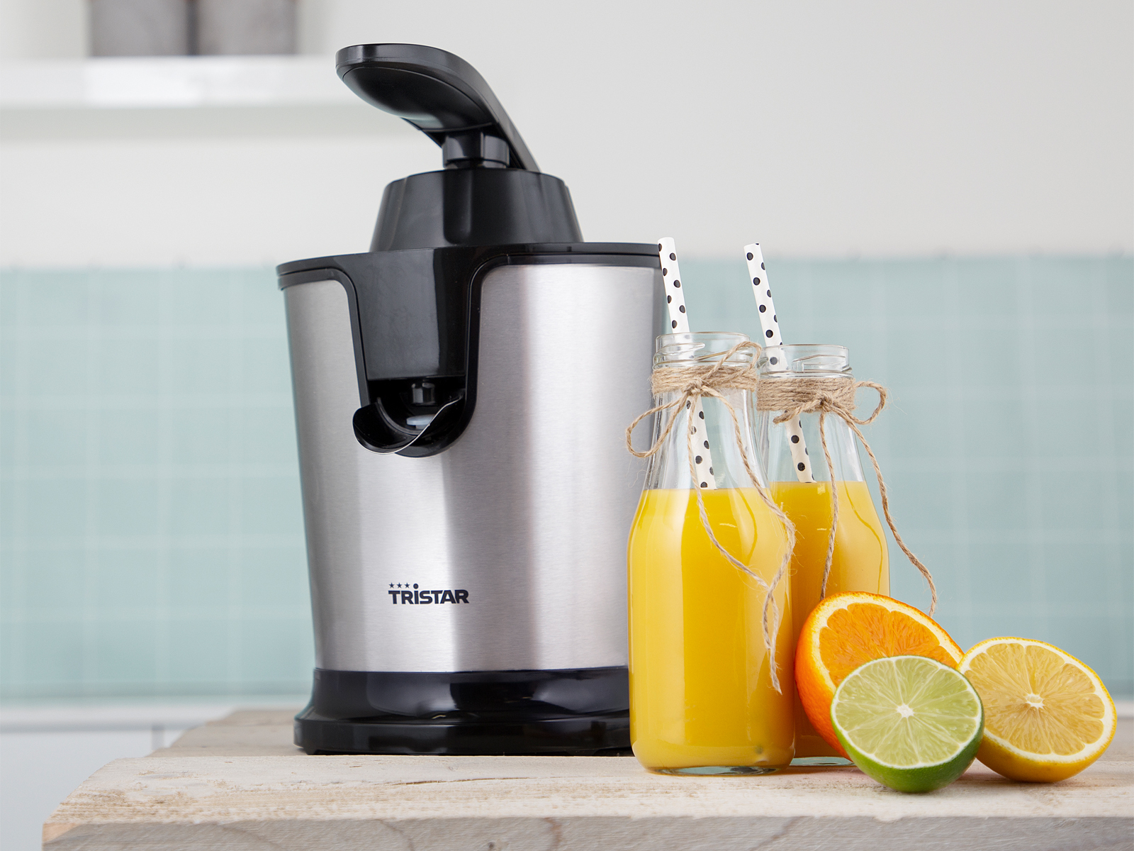 Wyciśnięta sokowirówka z dwiema butelkami soku ze słomkami. Pokrojone owoce obok.