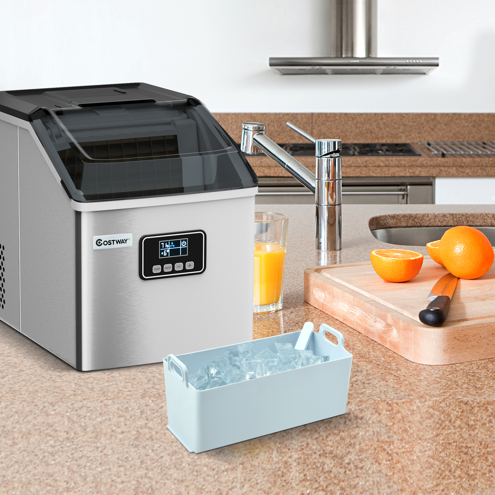 Eine Eismaschine und eine Schale mit Eiswürfeln auf einer Arbeitsplatte mit Orangen und einem Messer.
