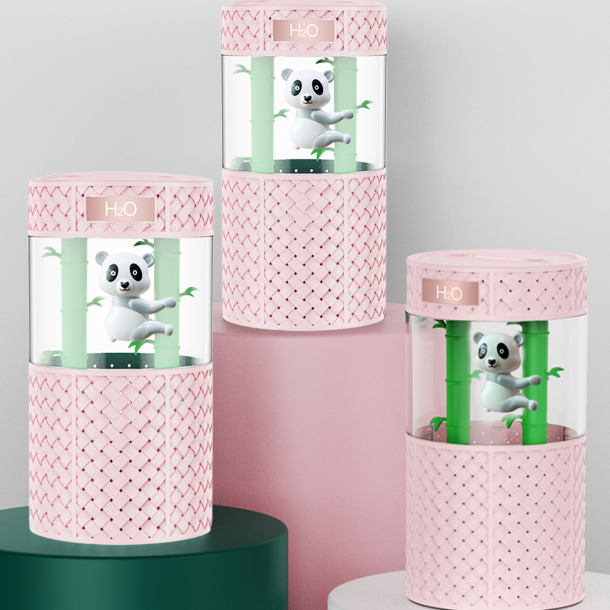 Drei rosa panda-förmige Luftbefeuchter mit Bambusdesign, gestapelt auf einer rosa Plattform, vor weißem Hintergrund.