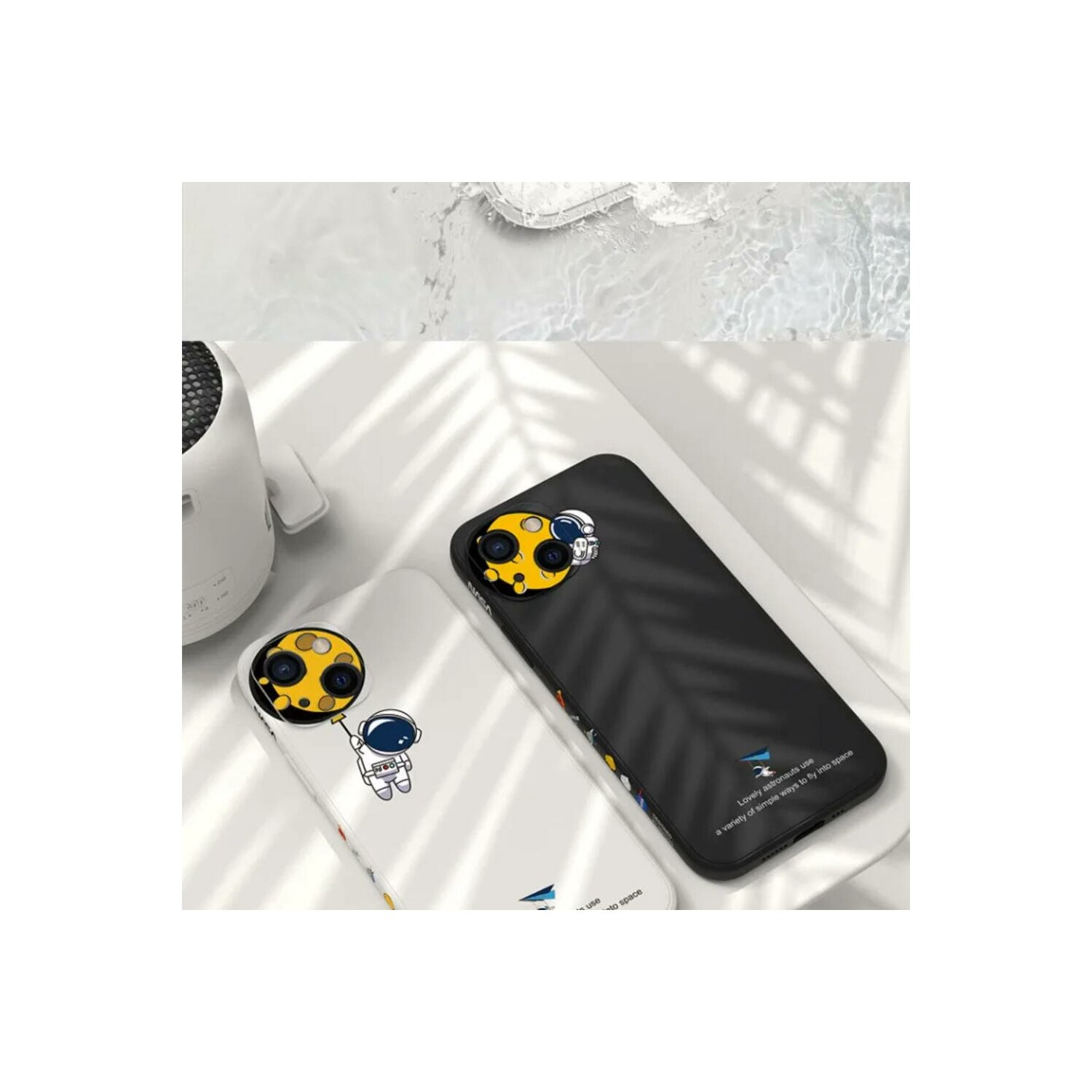 Zwei Handyhüllen, eine schwarze und eine weiße, mit Astronauten-Designs. Beide auf weißer Oberfläche, mit unscharfem Hintergrund.