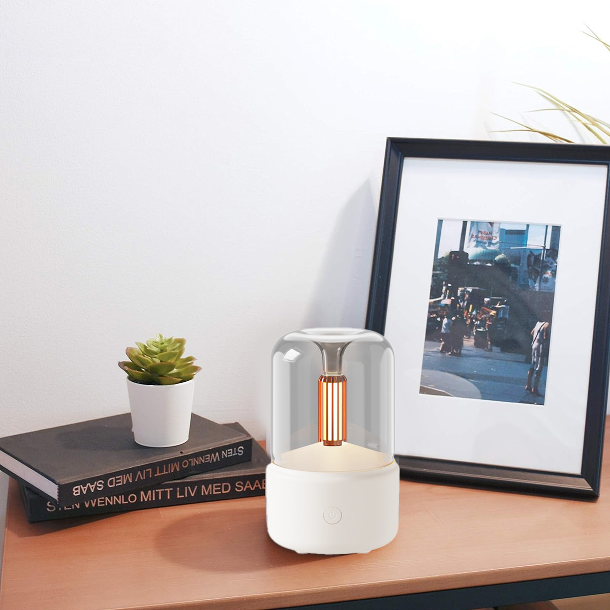 Moderne Lampe mit Pflanze und gerahmtem Bild auf einem Holztisch.