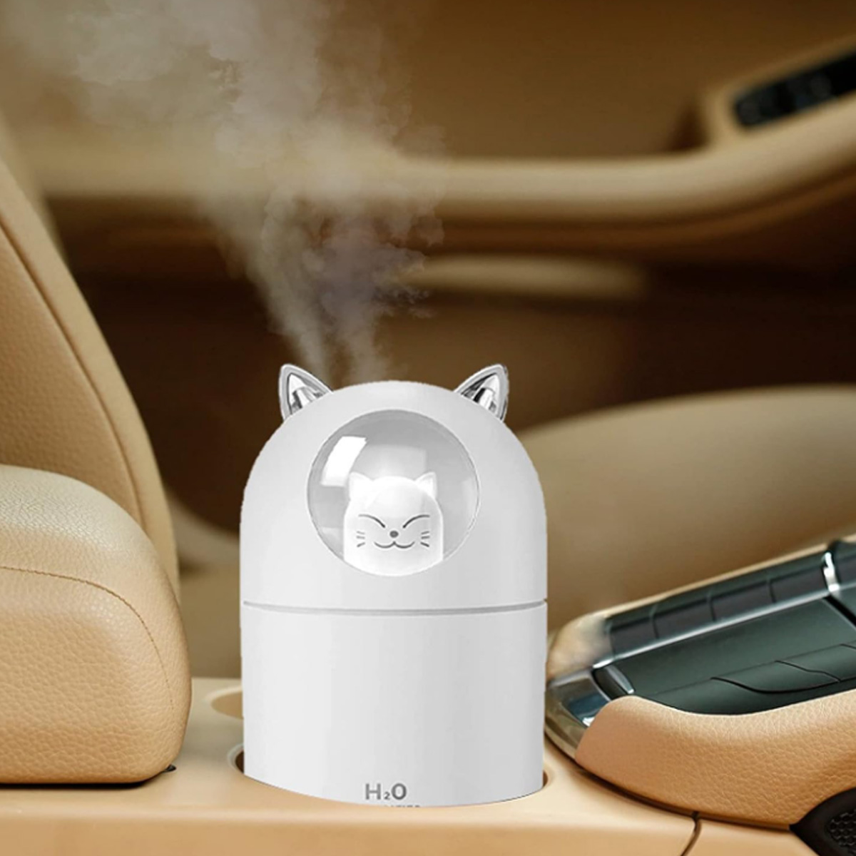 Weißer, katzenförmiger Aromadiffusor in einem Autobecherhalter. Nebel kommt heraus. Beige Innenausstattung.