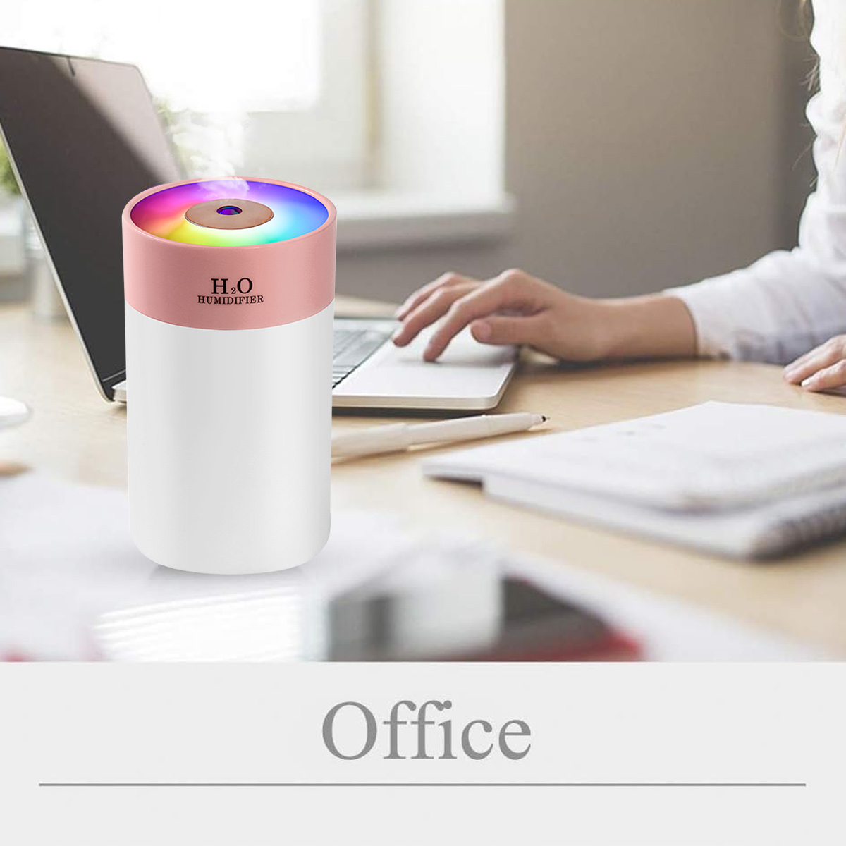 Luftbefeuchter auf einem Schreibtisch, Laptop geöffnet. Rosa und weißer Luftbefeuchter mit Regenbogenlicht, Büro.