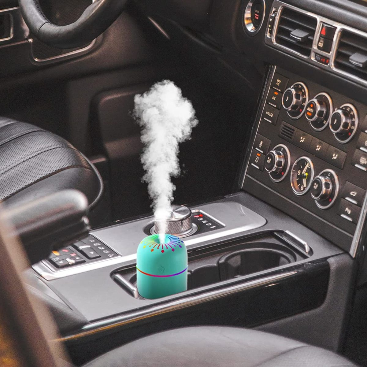 Ein kleiner Luftbefeuchter, der Dampf in der Mittelkonsole eines Autos abgibt. Regenbogenfarbene Spitze.