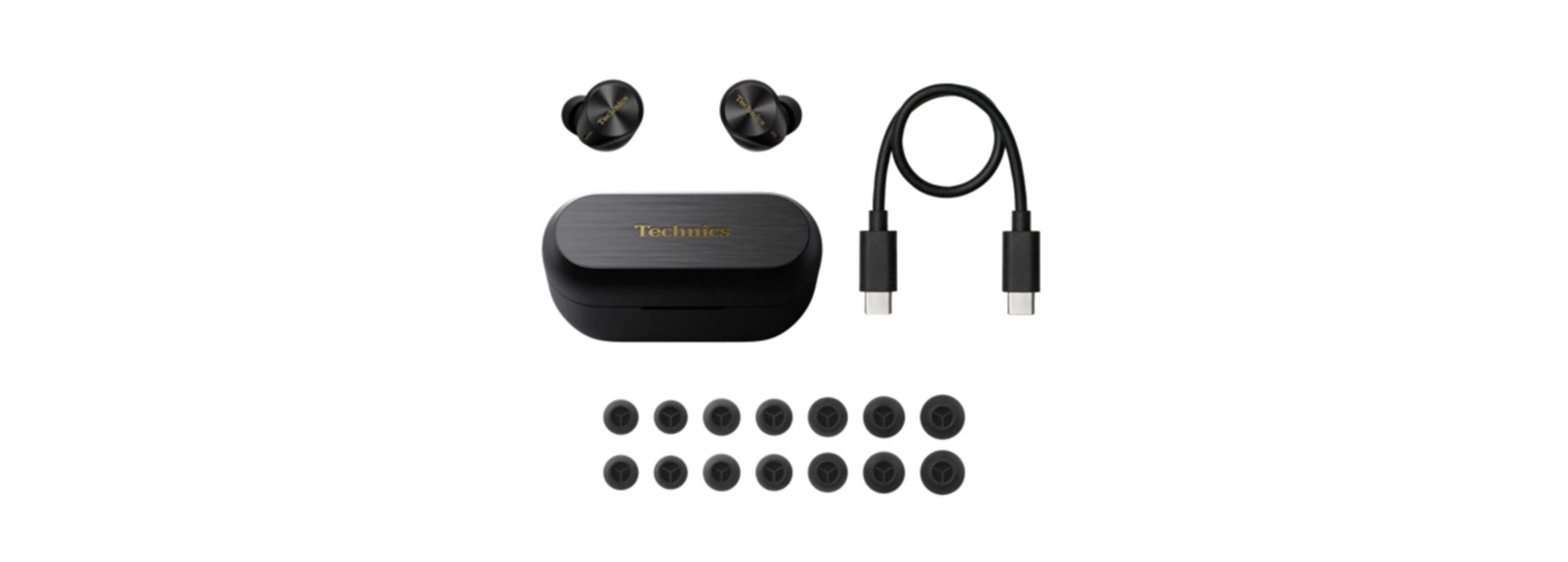 Schwarze Technics-Ohrhörer, Ladeetui und USB-C-Kabel mit zusätzlichen Ohrstöpseln auf weißem Hintergrund.