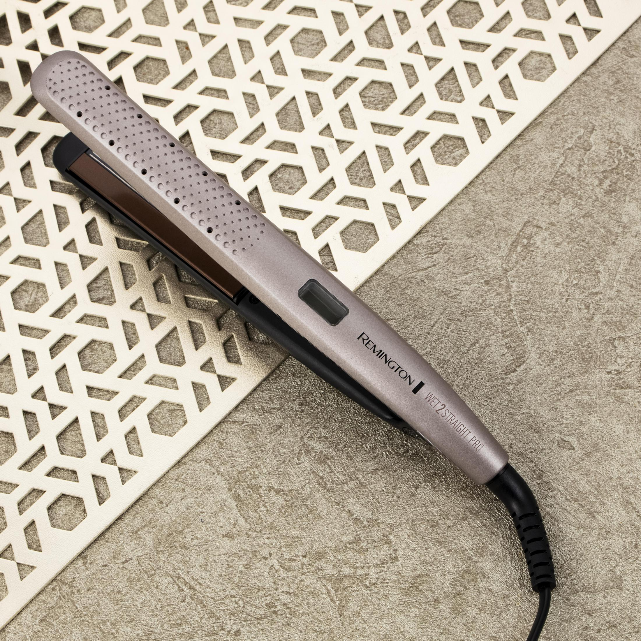 Piastra per capelli su superficie bianca decorativa, marca Remington. Grigio e nero con cavo.