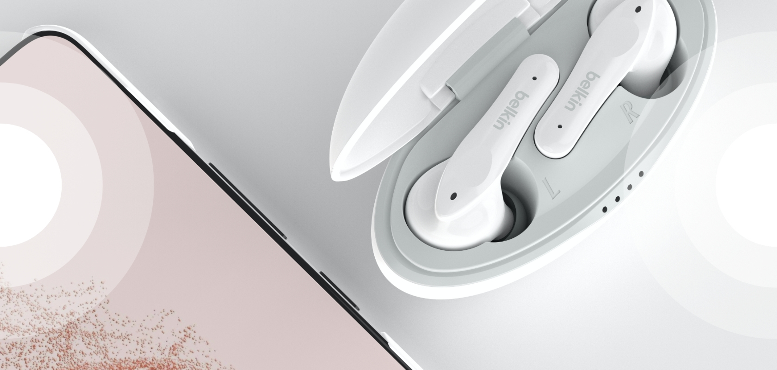 Białe słuchawki w etui ładującym obok smartfona.