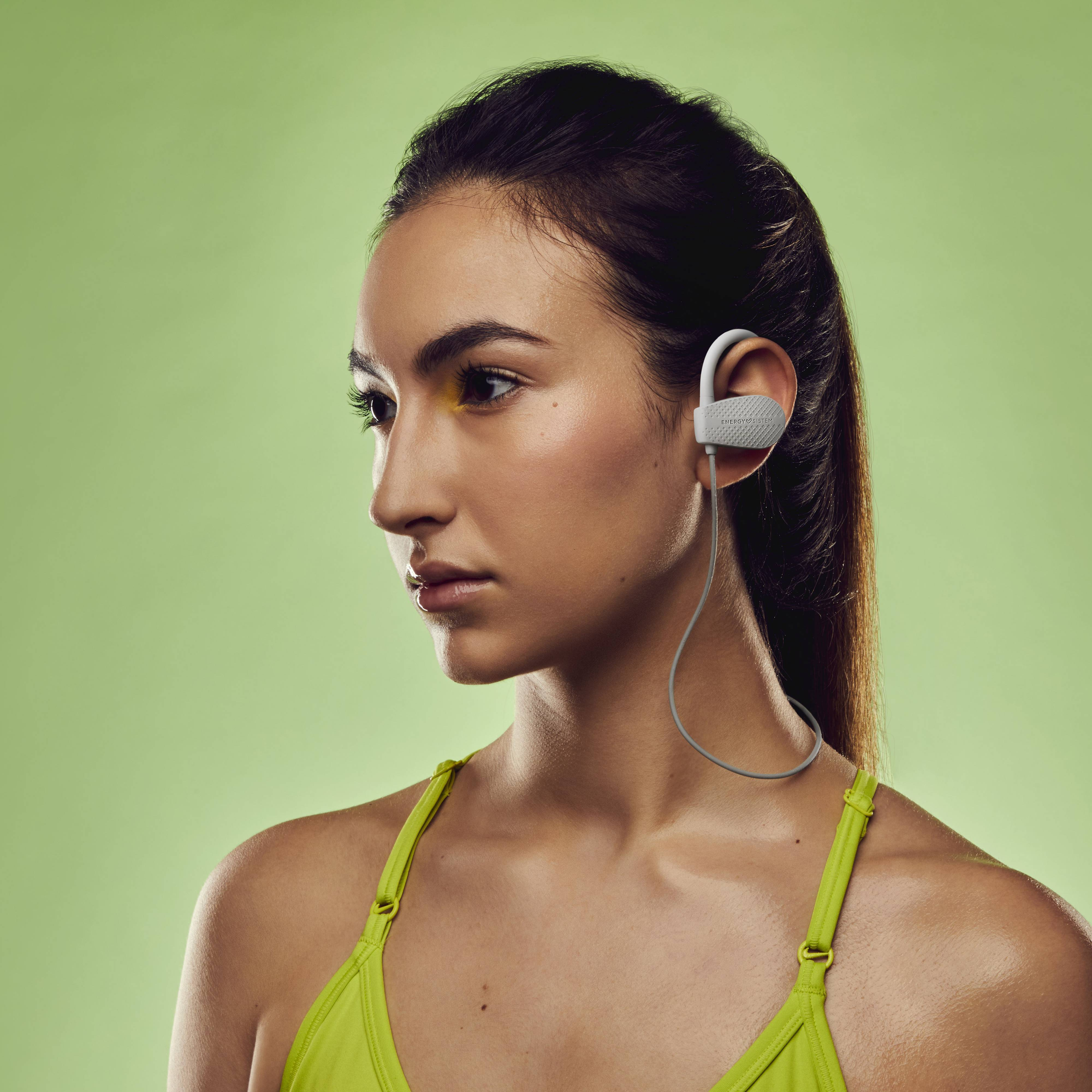 Donna con cuffie wireless bianche, rivolta a sinistra, sfondo verde.