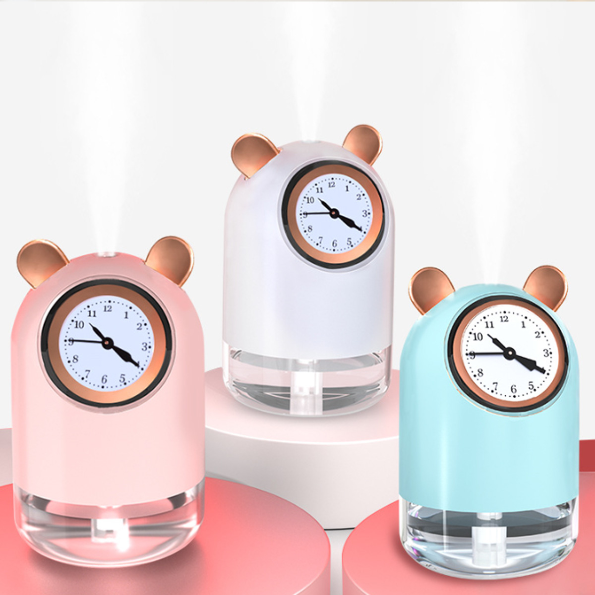 Drei Bärenohren-Luftbefeuchter, rosa, weiß und blau, jeweils mit Zifferblatt, die Dampf abgeben.