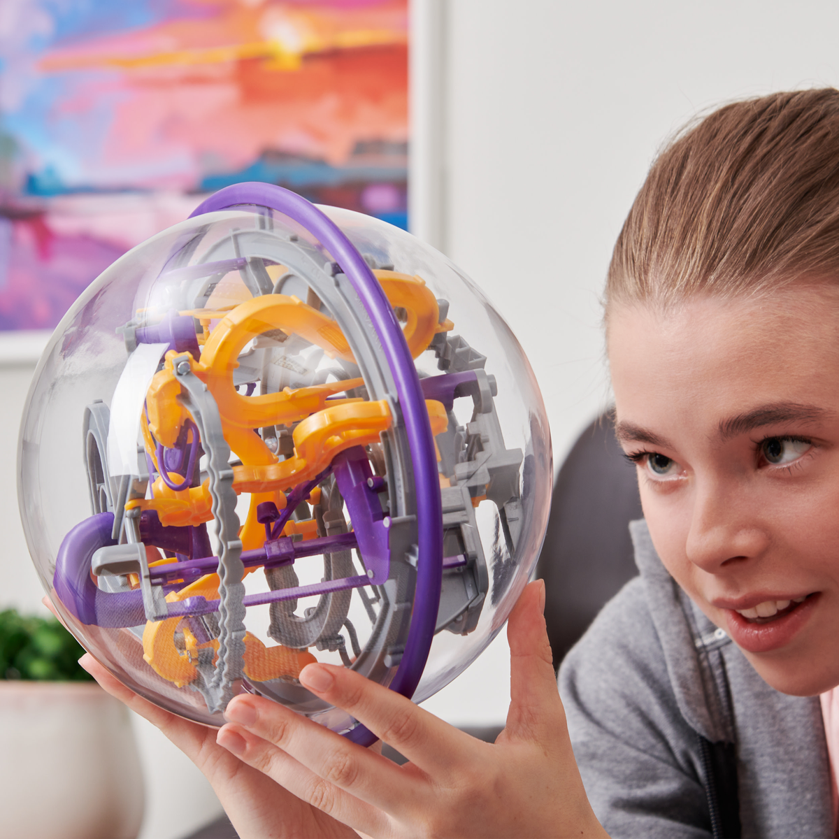 Ragazza che tiene una palla puzzle trasparente con componenti interni gialli e viola.