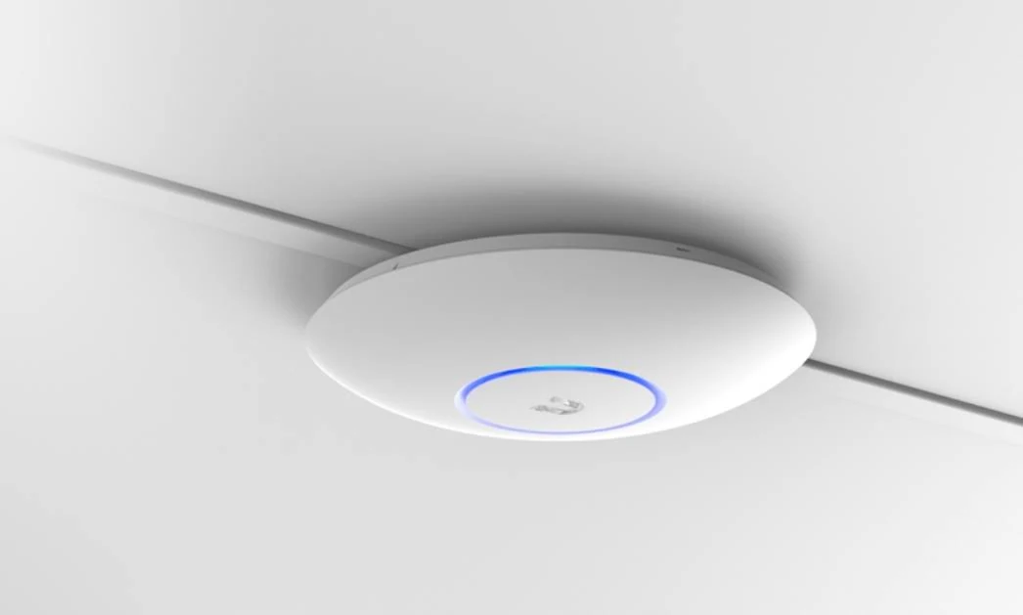 Biały, okrągły punkt dostępowy montowany na suficie z niebieskim pierścieniem świetlnym i kablem.