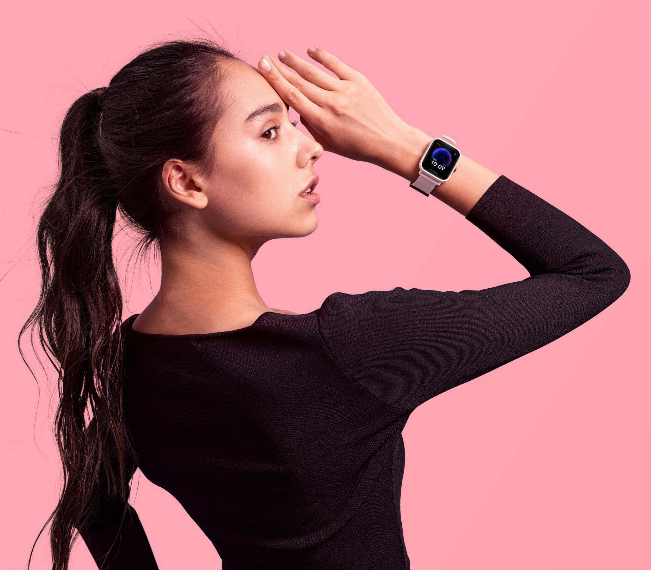 Una giovane donna con un top nero con uno smartwatch al polso, che guarda altrove.