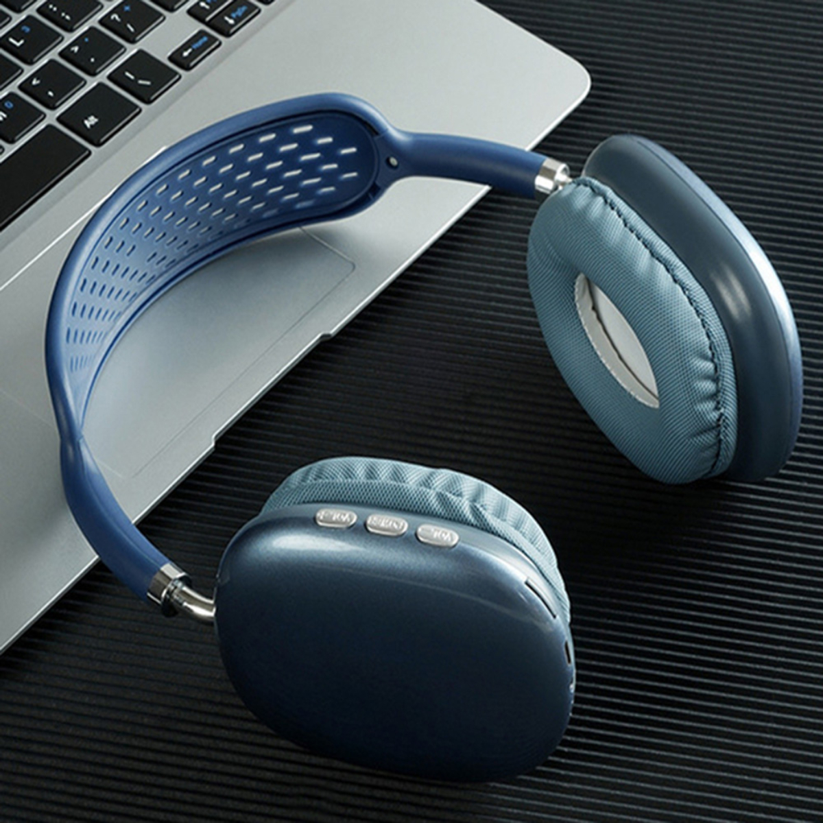 Auriculares sobre un portátil. Los auriculares son azules y grises. El portátil está abierto sobre un escritorio.
