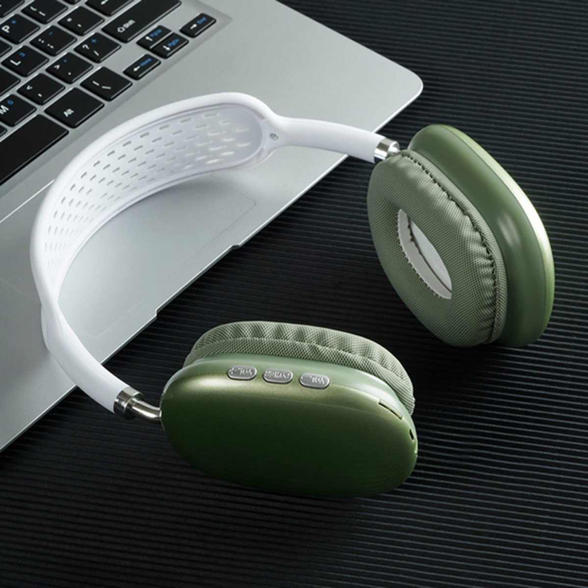 Auriculares con banda blanca y auriculares verdes se colocan en una computadora portátil. El fondo es negro.