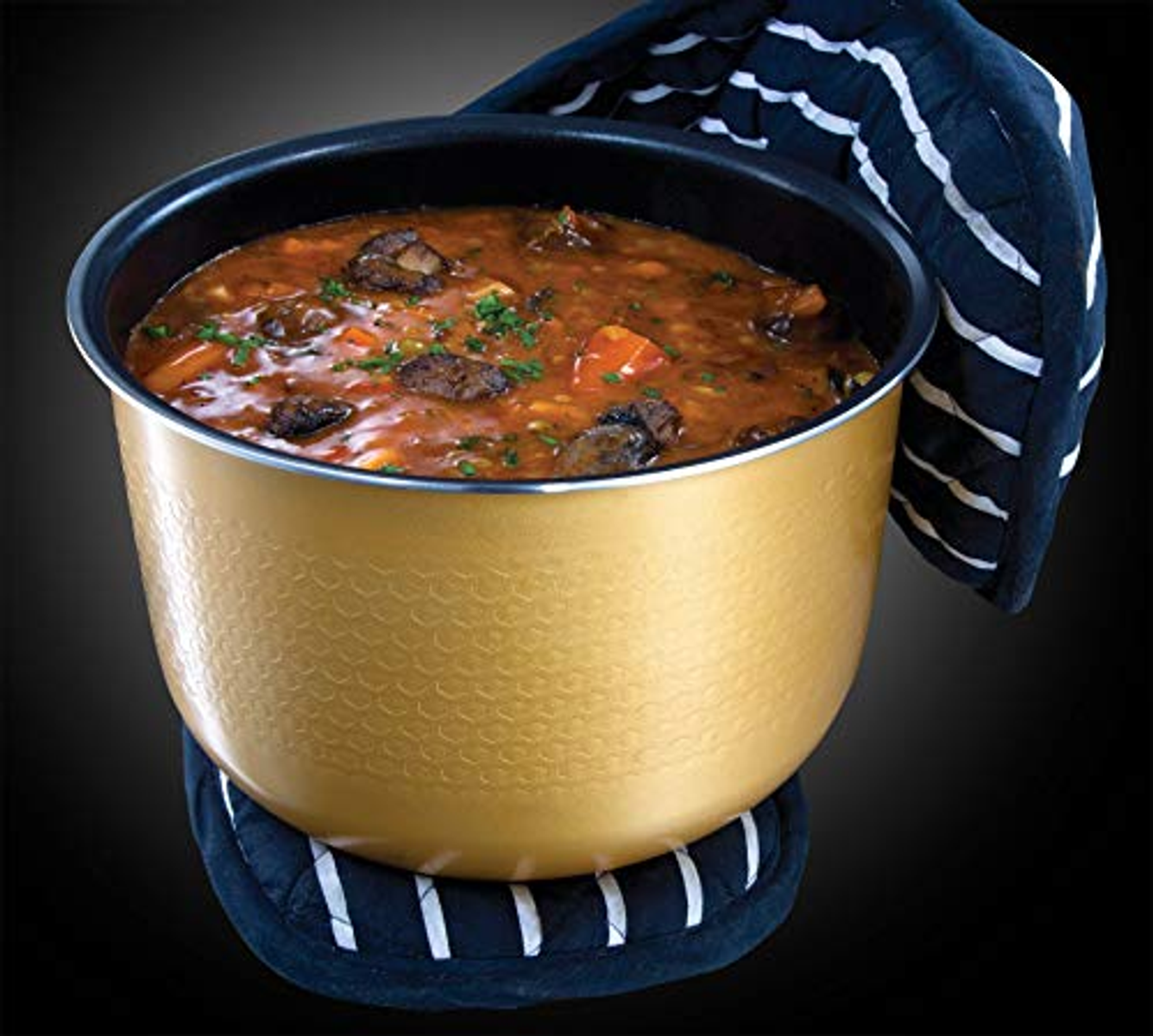 Une marmite dorée de ragoût, carottes et viande visibles. Elle est placée sur un dessous de plat rayé bleu marine et blanc.