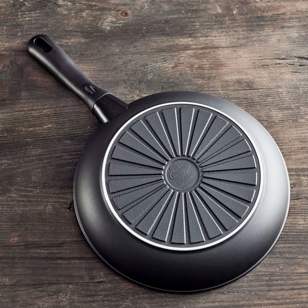 Czarna patelnia, widok od spodu, z teksturowaną powierzchnią.