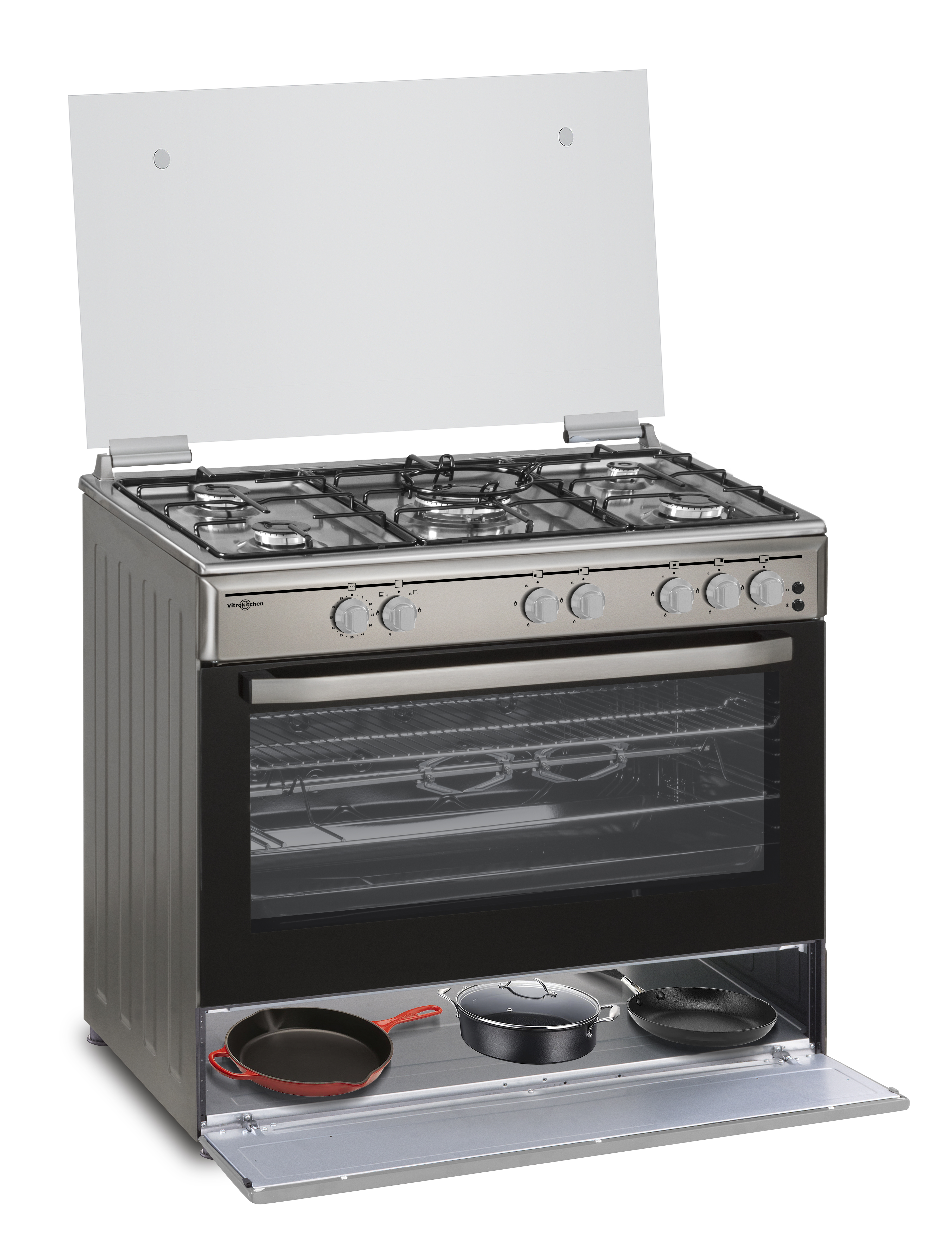 Una cocina de gas de acero inoxidable con horno y tapa de cristal. Hay sartenes en el cajón inferior.