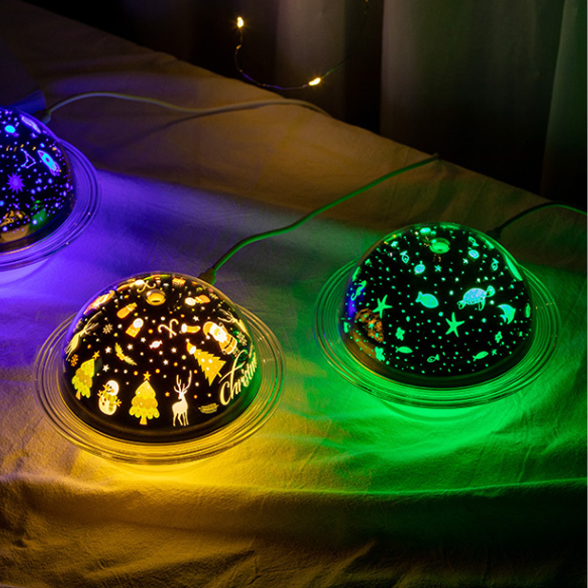 Zwei Planetarium-Projektoren auf einem Bett. Sie sind schwarz mit bunten Szenen.
