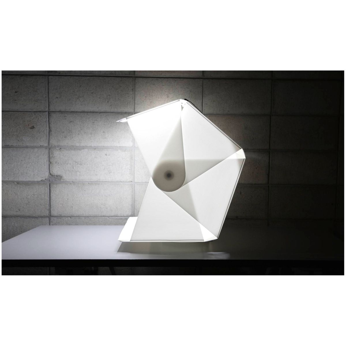 Weiße Origami-Lampe auf grauer Oberfläche.