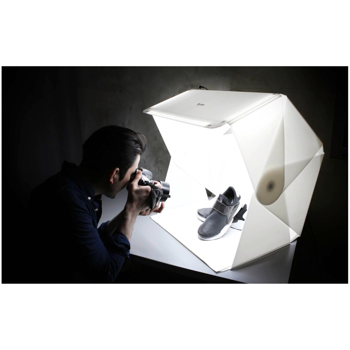 Eine Person fotografiert einen Schuh in einer weißen Fotografie-Leuchtbox.