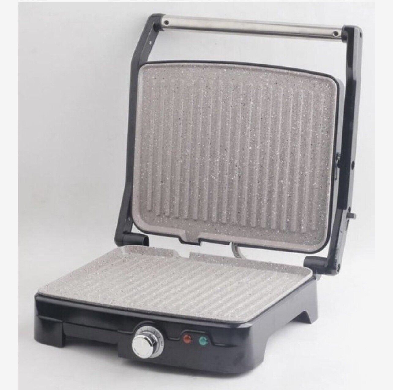 Ein offener schwarzer Grill mit grau gemusterter Oberfläche. Der Grill hat einen Drehknopf und ein Licht.