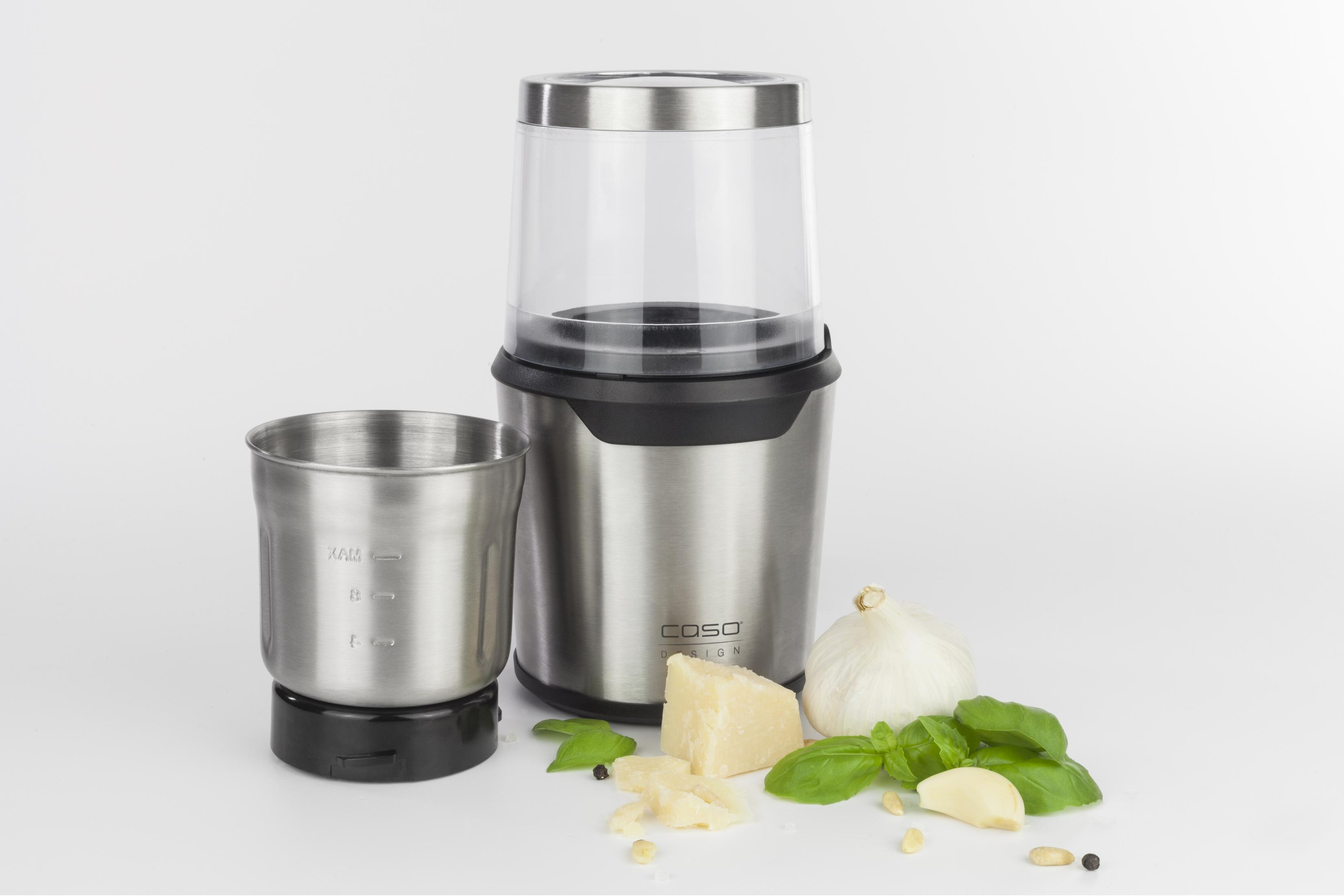 Un robot da cucina con base in acciaio inossidabile. Accanto, ci sono ingredienti come basilico, formaggio e aglio.