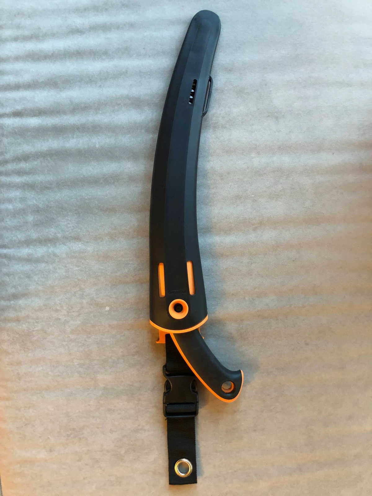 Schwarz-oranges Machete mit schwarzer Scheide, mit Riemen hängend, liegend auf Oberfläche.