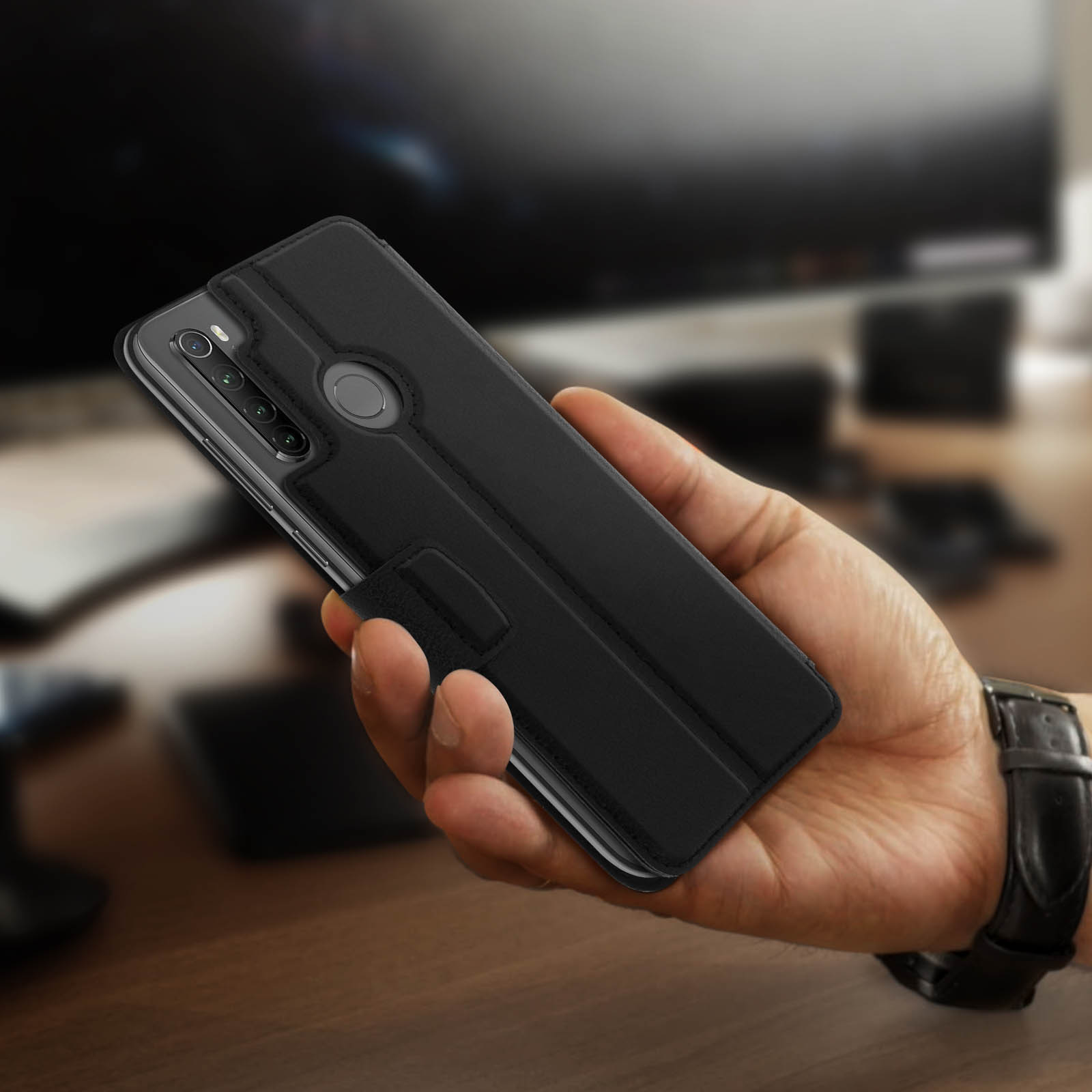 Una custodia per telefono nera in mano. La custodia è aperta, mostrando un telefono con fotocamera e schermo.